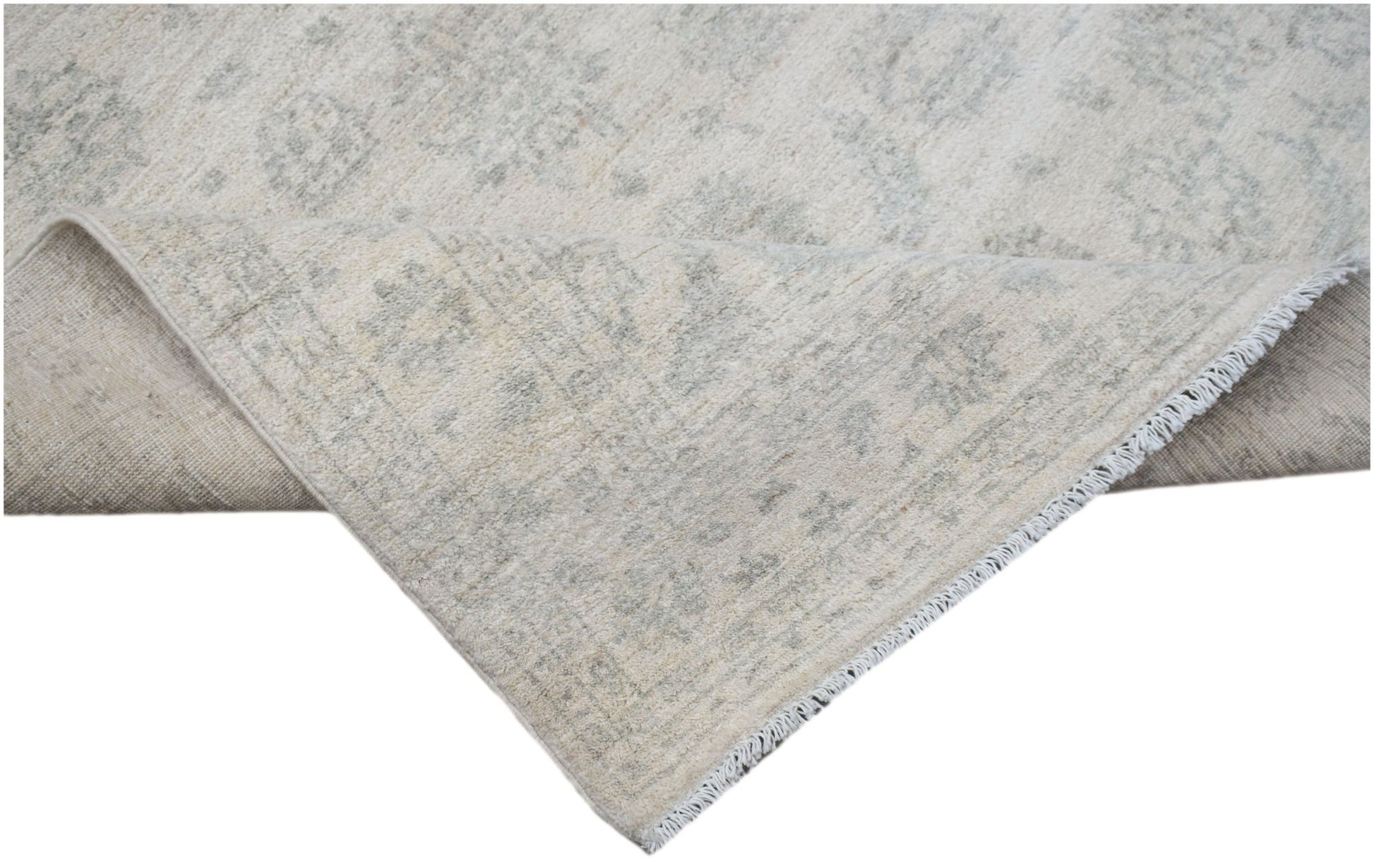 A handmade Afghan Chobi rug with a light beige and grey floral pattern and a fringed edge.