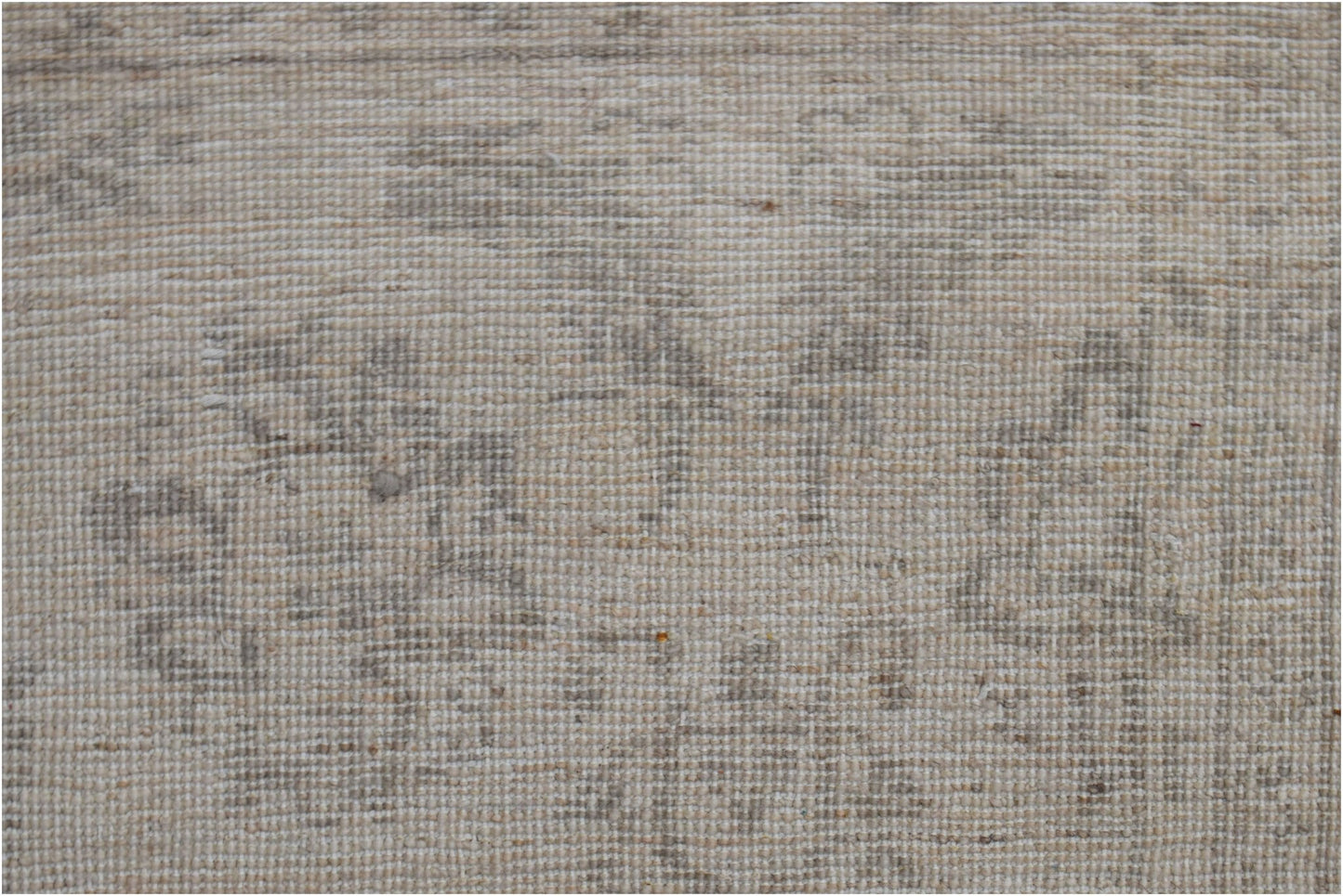 A close-up of a handwoven Afghan Chobi rug featuring a subtle, neutral-toned traditional pattern.