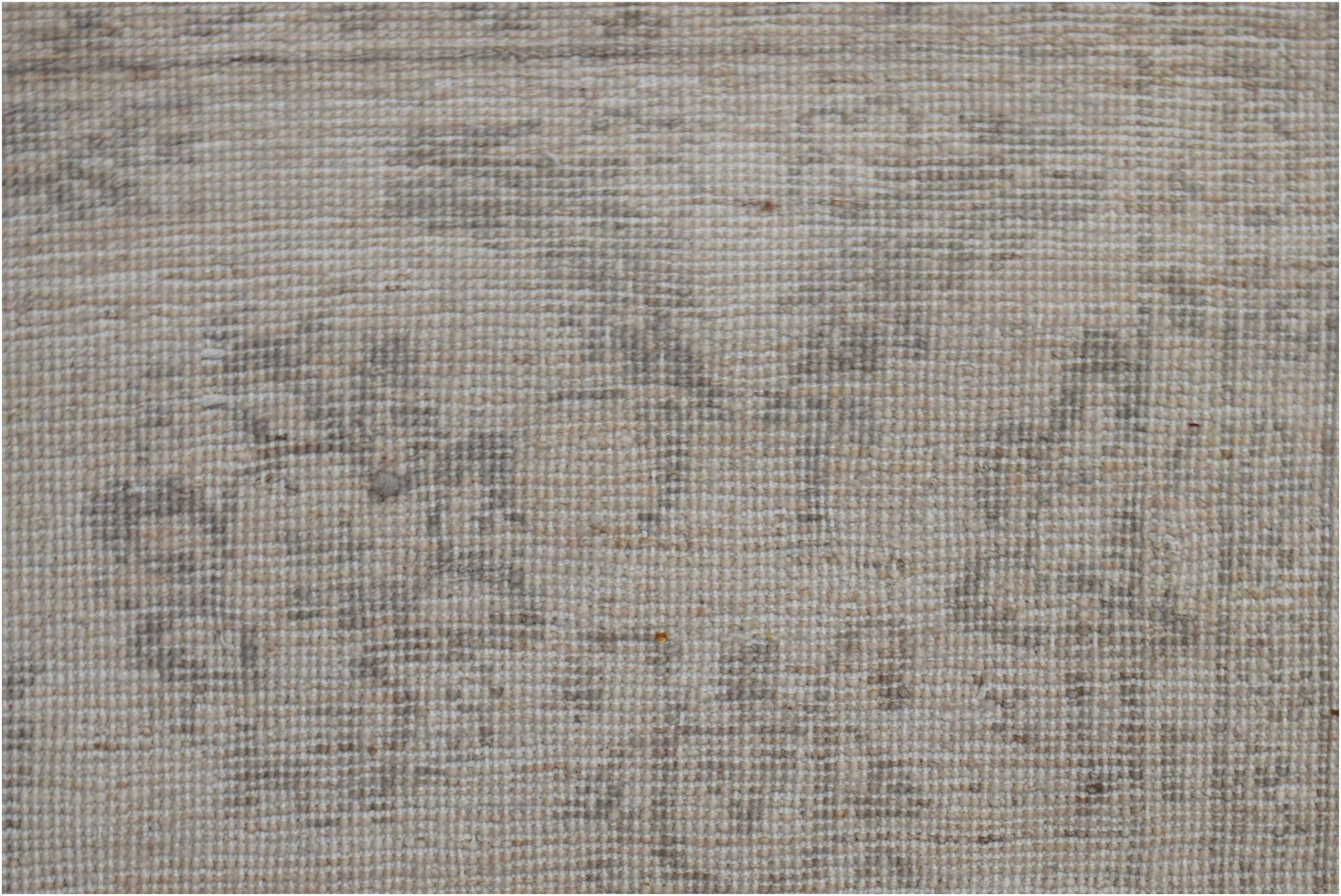 A close-up of a handwoven Afghan Chobi rug featuring a subtle, neutral-toned traditional pattern.
