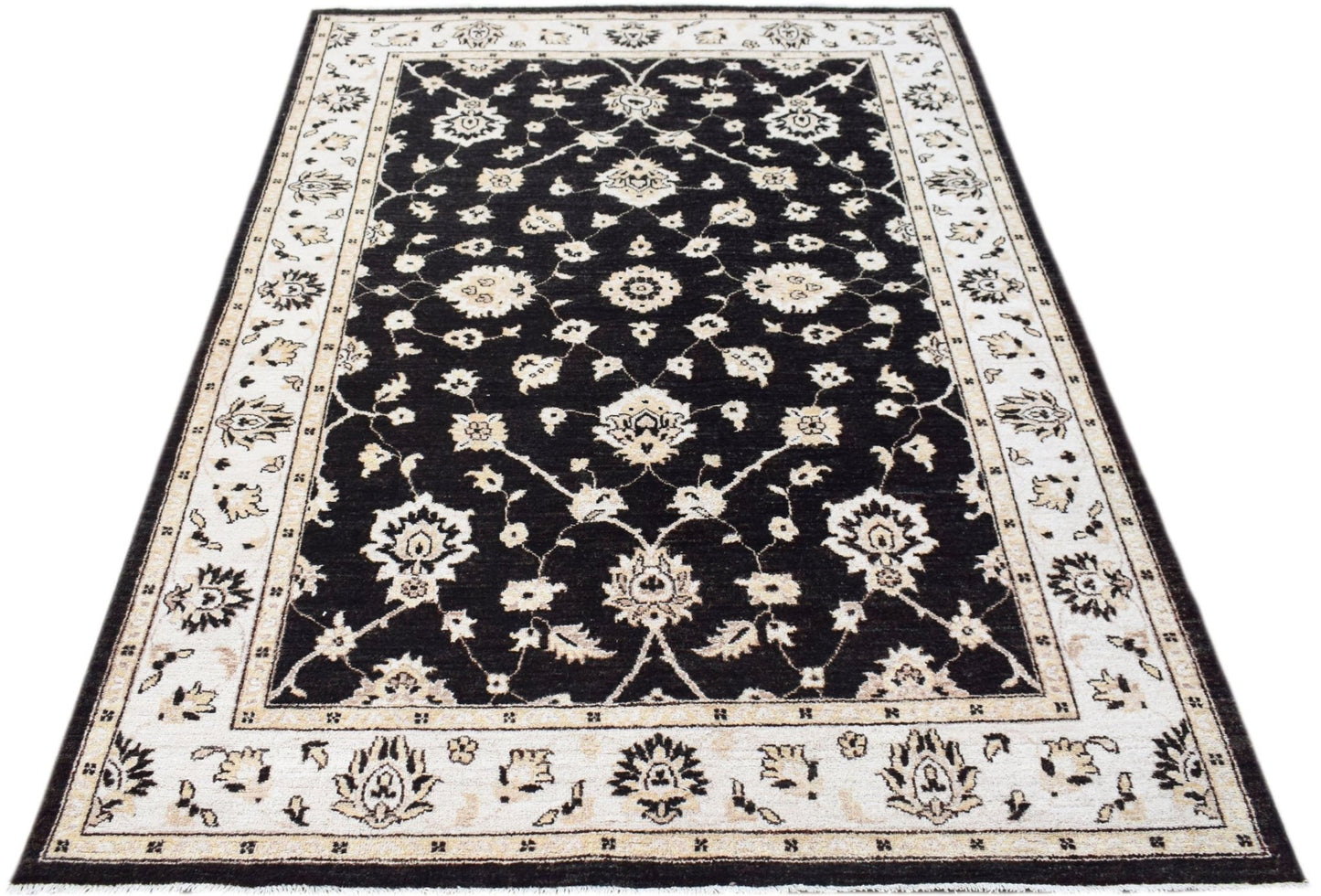 A rectangular Afghan Chobi rug featuring a black field with intricate cream floral patterns.