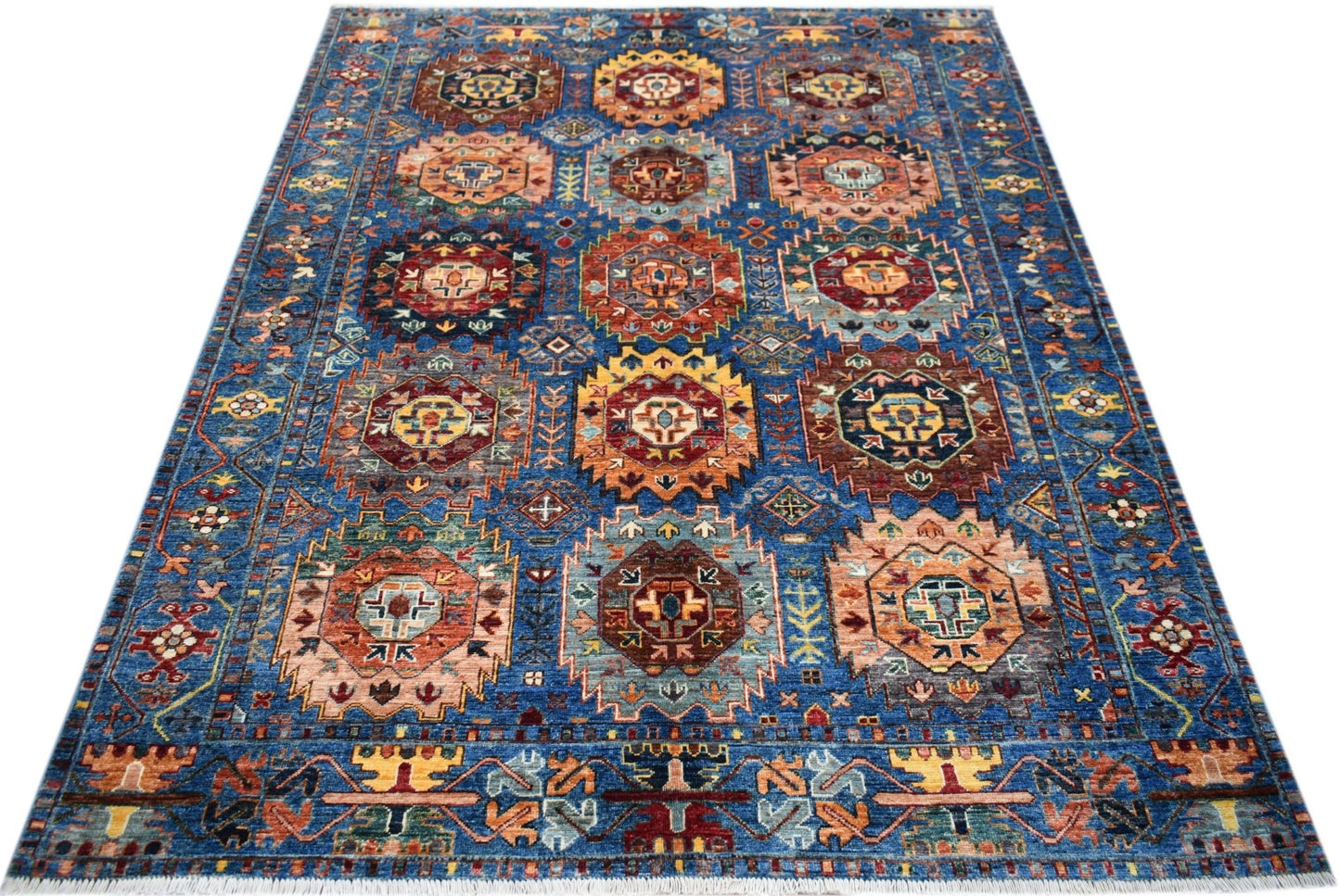 A handmade Afghan Chobi rug featuring a blue field with repeating geometric medallion patterns.