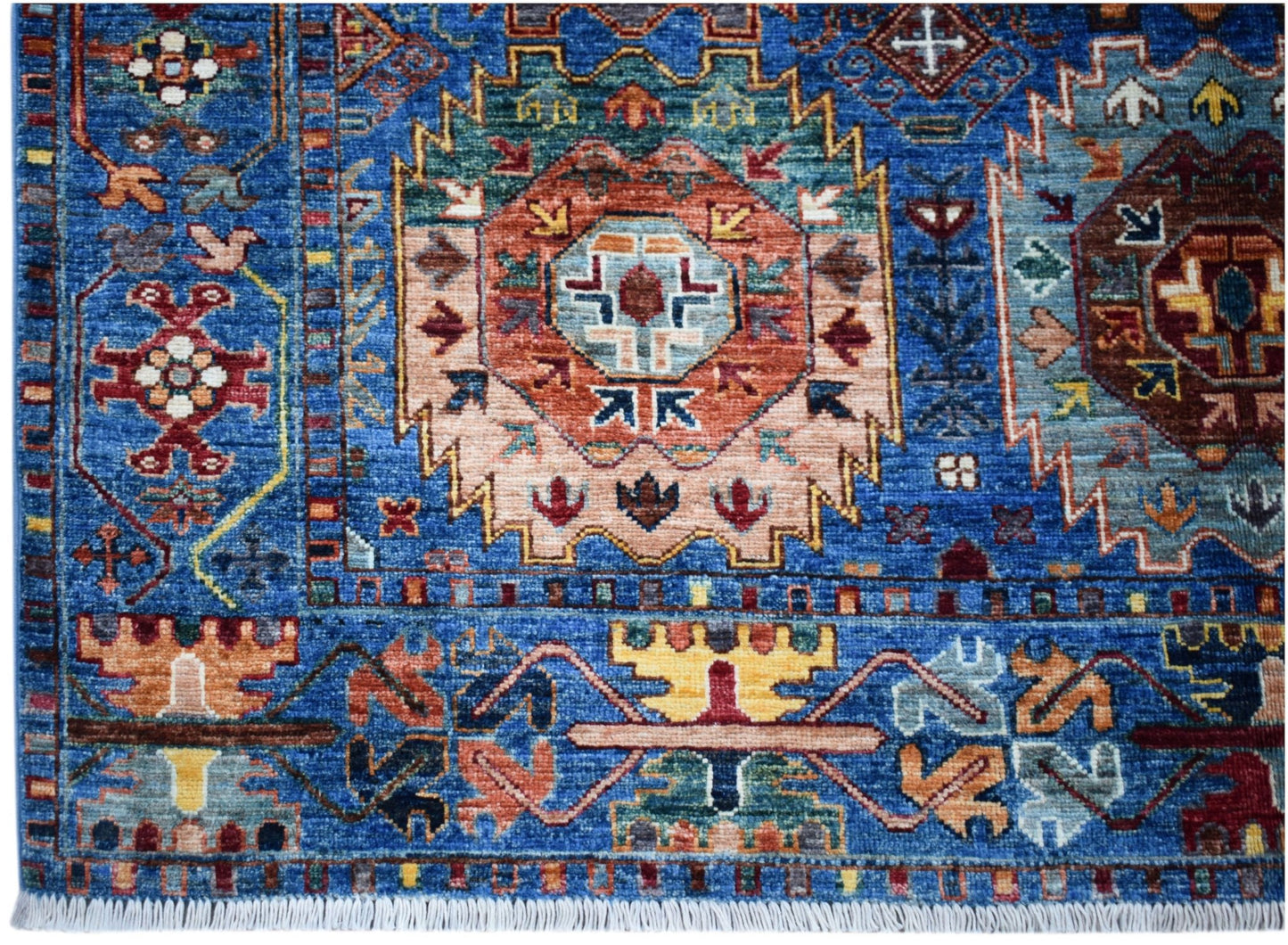 A handwoven Afghan Chobi rug featuring a vibrant blue field with intricate geometric patterns.