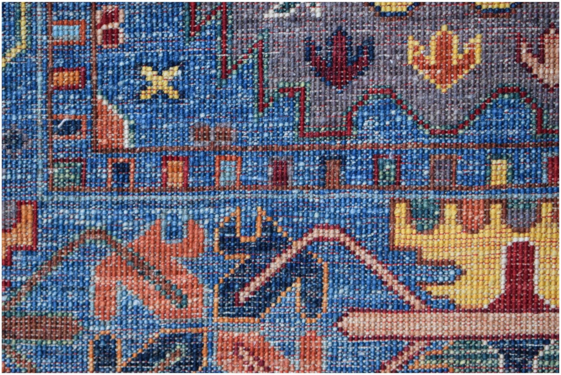 A close-up of a handwoven Afghan Chobi rug featuring intricate geometric patterns in blue and gold.