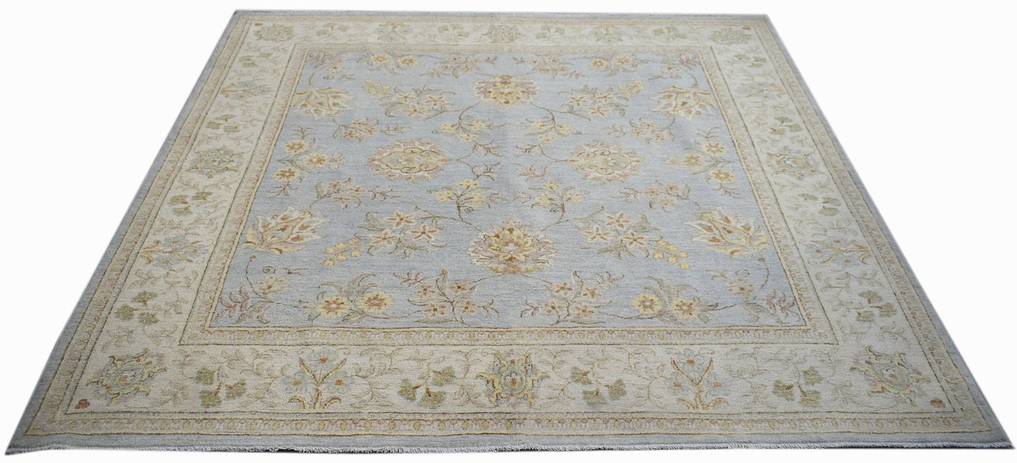 A rectangular Afghan Chobi rug featuring a light blue field with floral patterns and a beige border.
