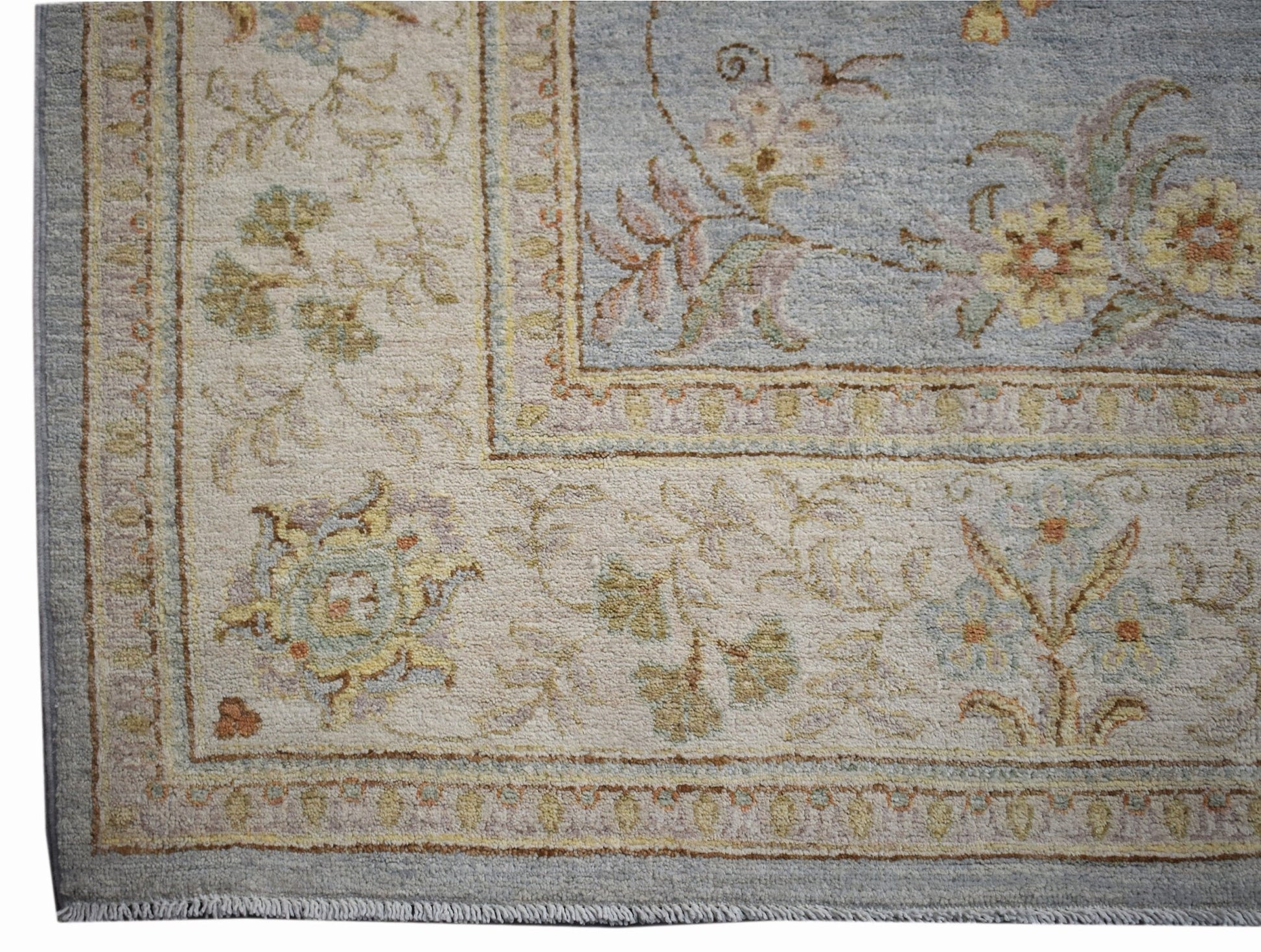 A handwoven Afghan Chobi rug featuring a floral pattern in soft blue and cream tones.