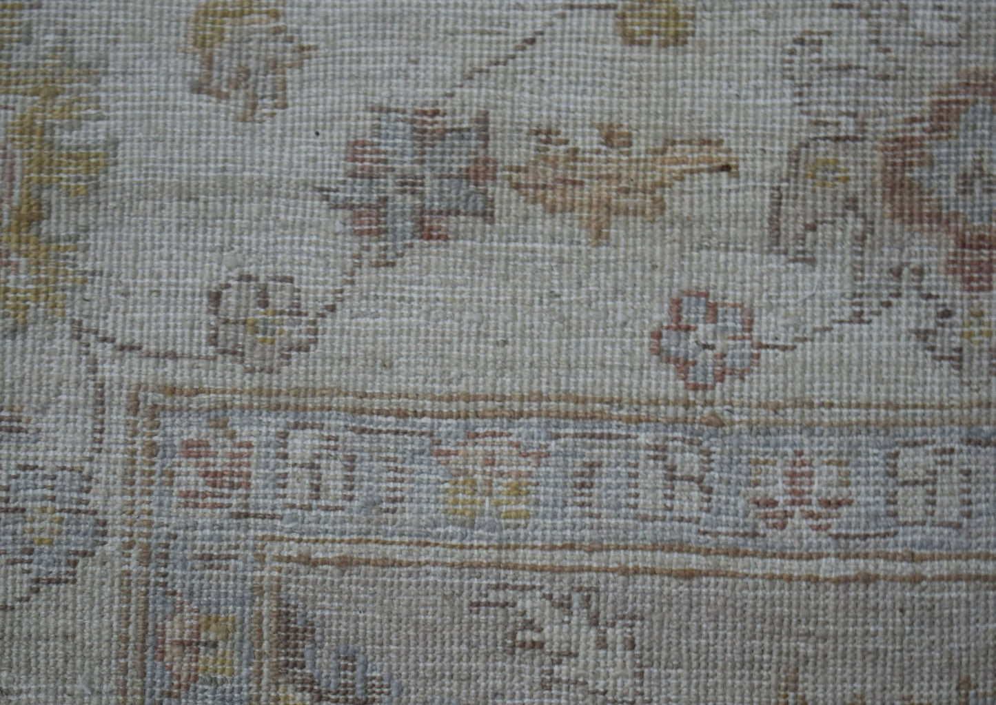 A close-up of a handwoven Afghan Chobi rug featuring traditional floral patterns in muted tones.