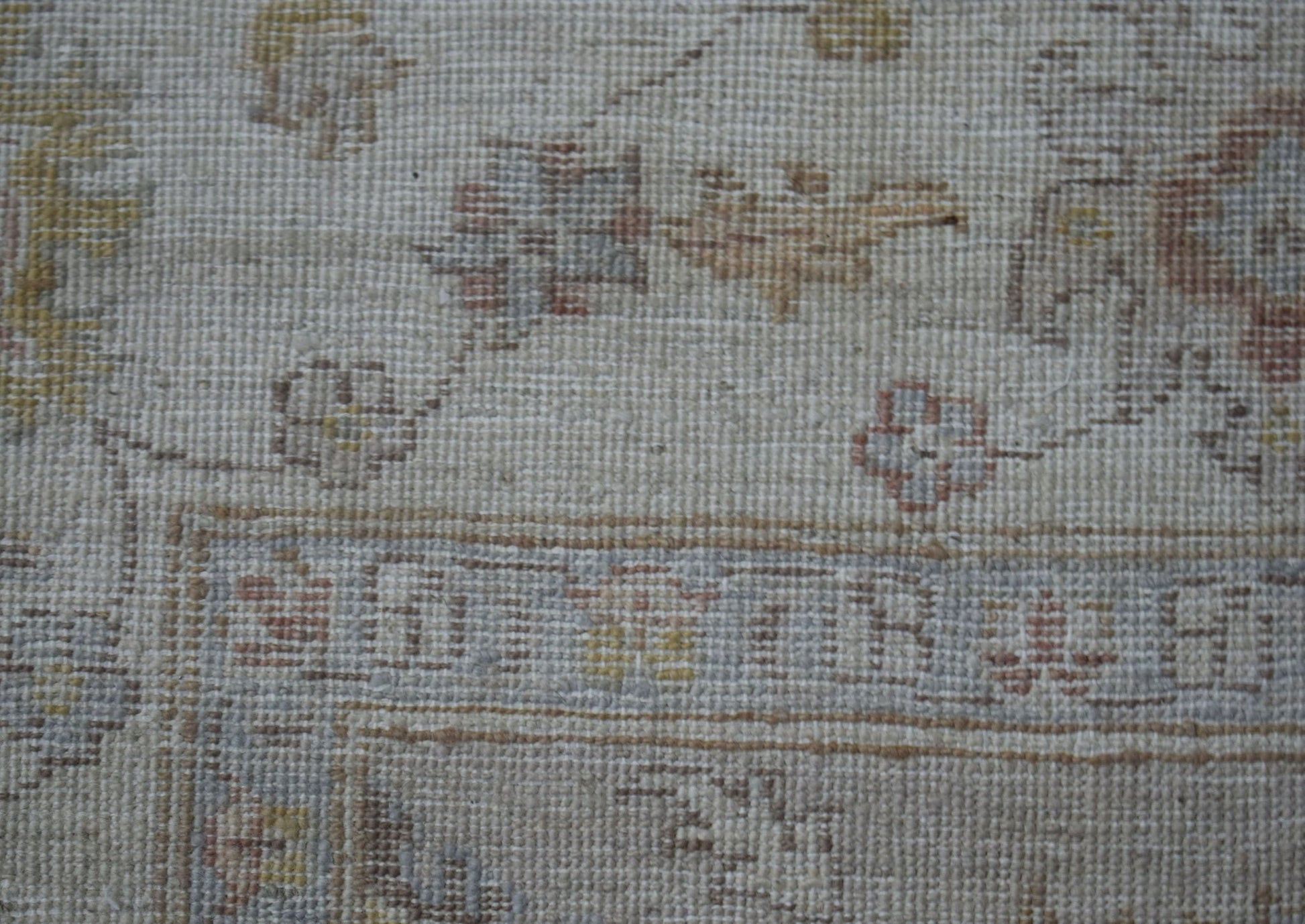 A close-up of a handwoven Afghan Chobi rug featuring traditional floral patterns in muted tones.