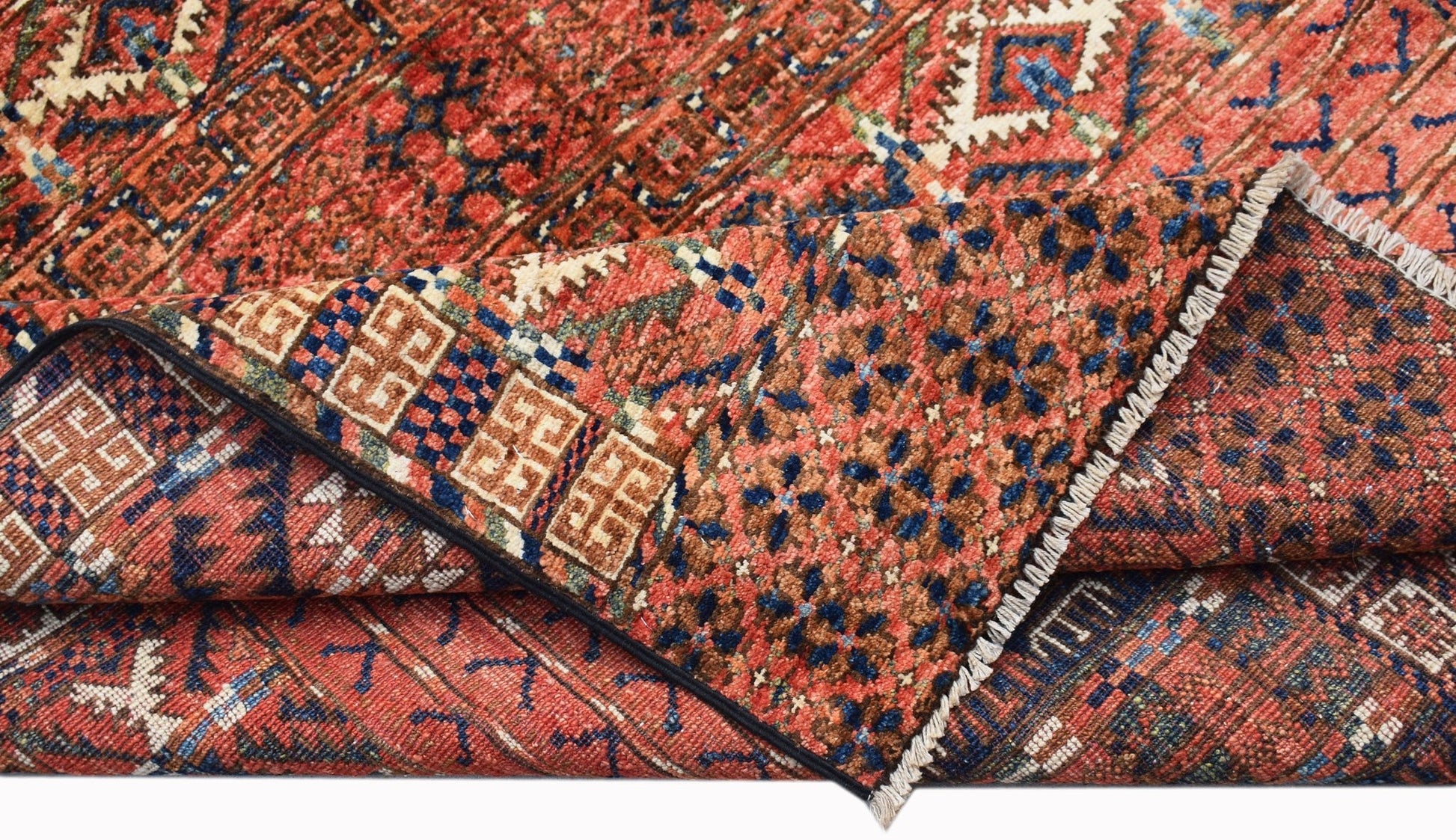 A folded Afghan Chobi rug featuring traditional geometric patterns in red, blue, and brown tones.