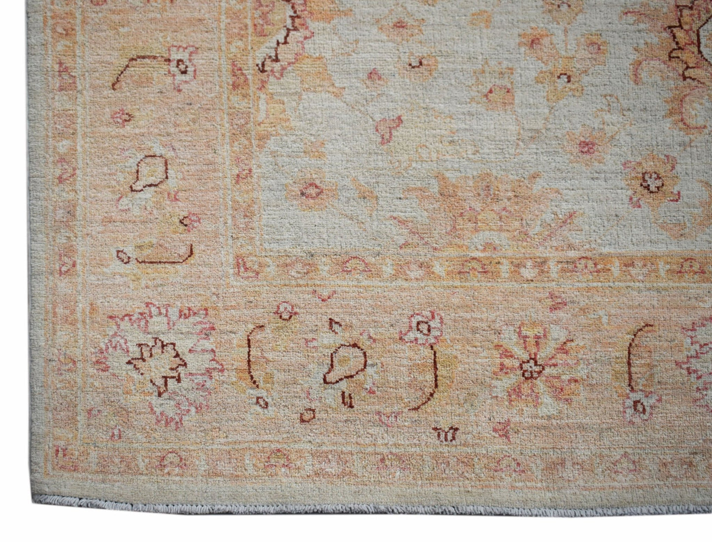 A handmade Afghan Chobi rug featuring a traditional floral pattern in soft peach and cream tones.