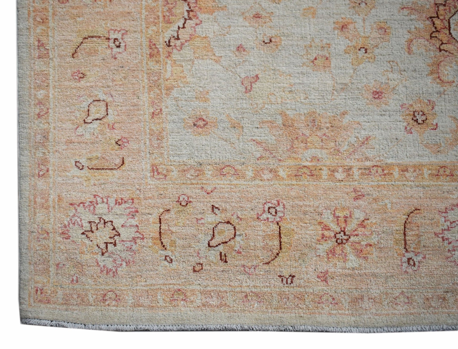 A handmade Afghan Chobi rug featuring a traditional floral pattern in soft peach and cream tones.