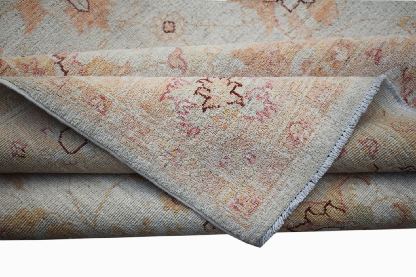 A folded Afghan Chobi rug featuring traditional floral patterns in soft beige and muted pink tones.