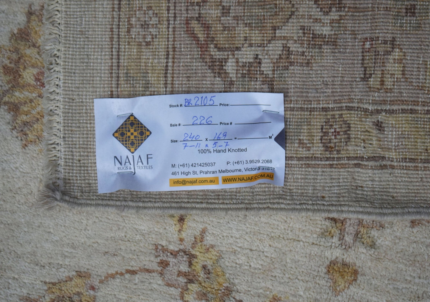 A close-up of a hand-knotted Afghan Chobi rug with a tag showing its dimensions and origin.
