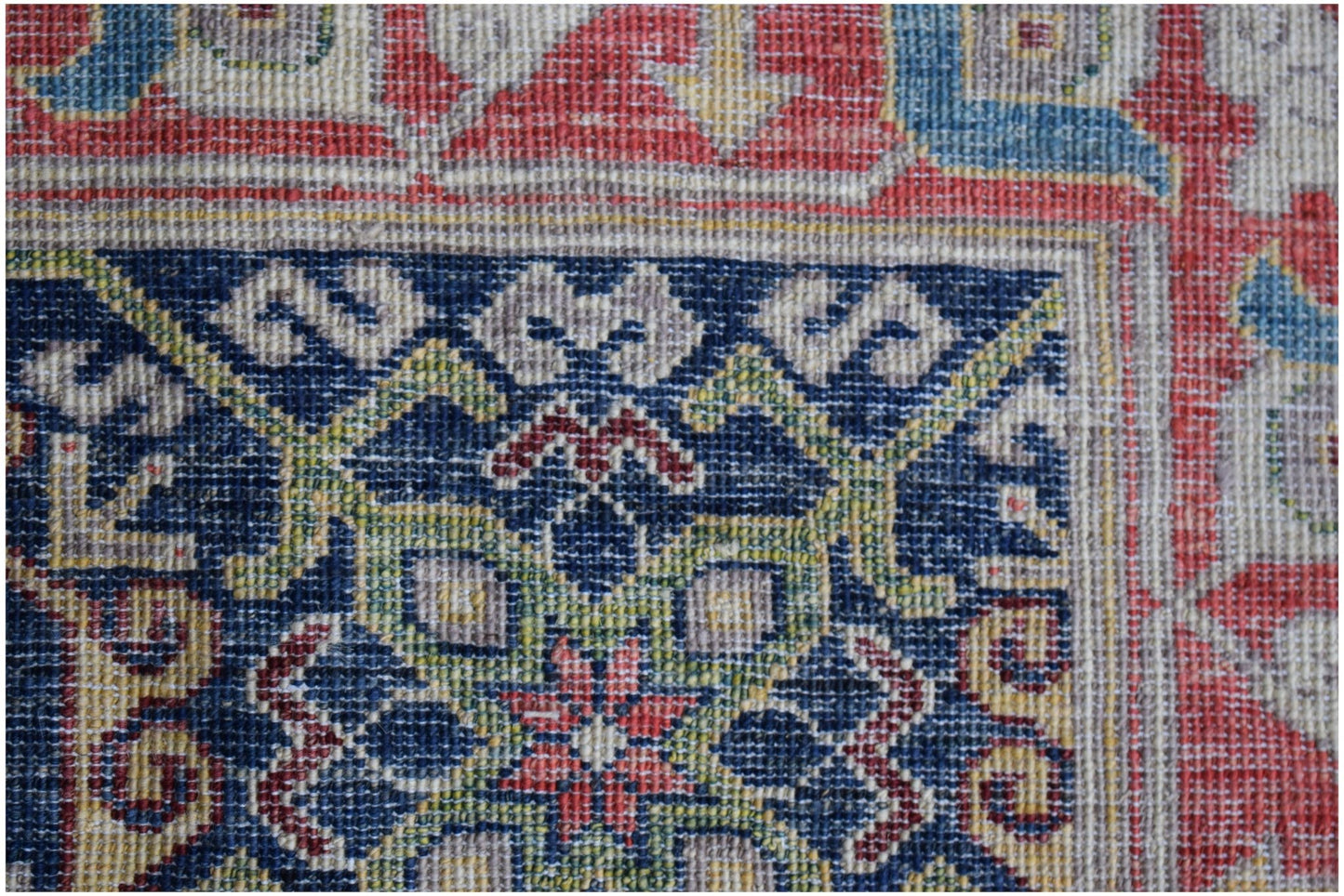 A close-up of an Afghan Chobi rug featuring intricate geometric patterns in blue, red, and yellow.
