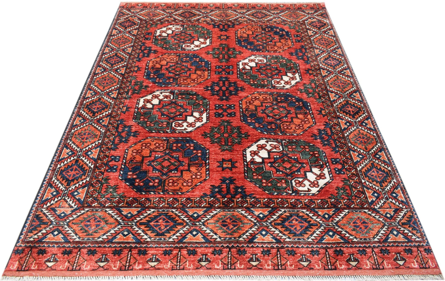 Handwoven Afghan Chobi rug featuring a red field with repeating geometric octagonal medallions.
