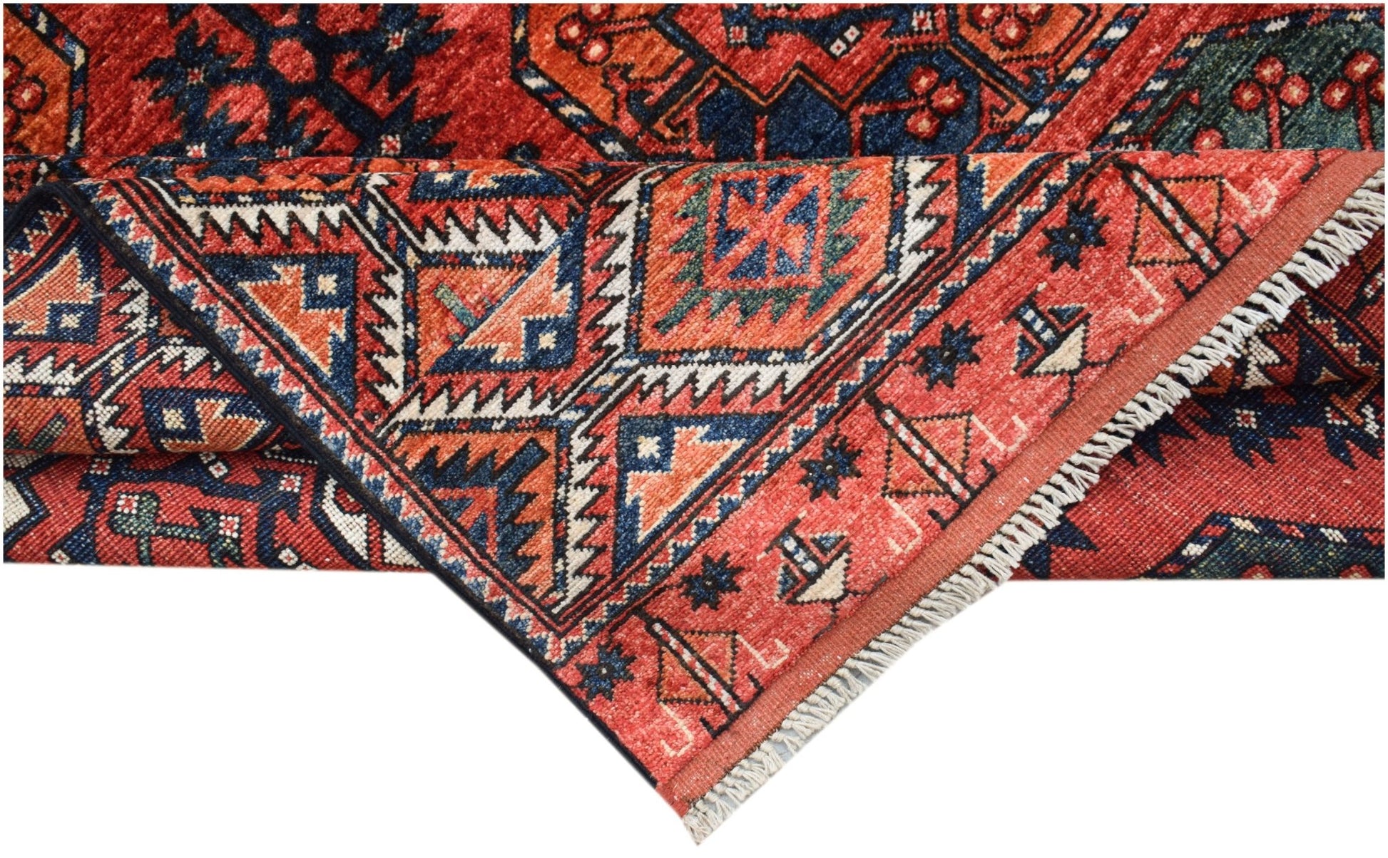 A corner of a handwoven Afghan Chobi rug featuring traditional geometric patterns in red and blue.