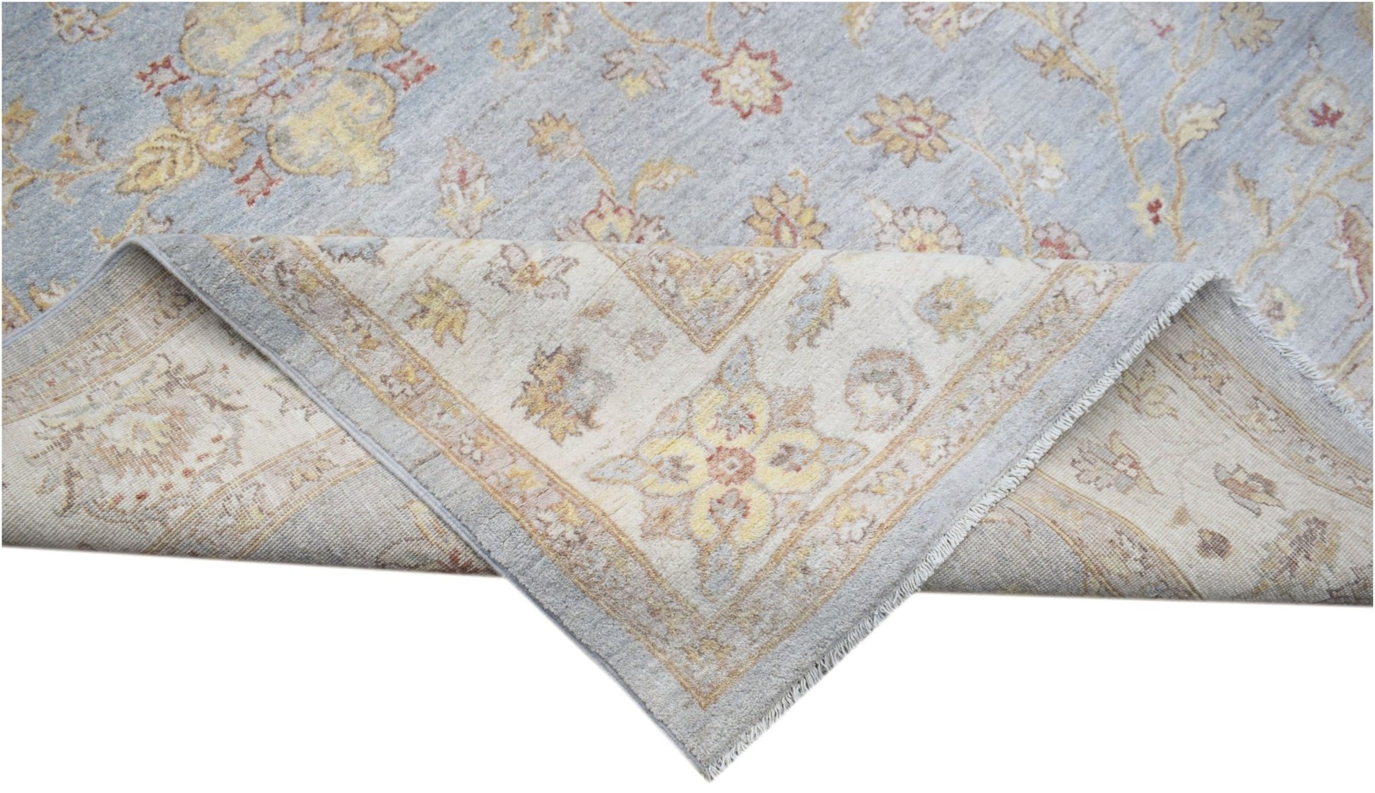 A handwoven Afghan Chobi rug featuring a light blue field with floral patterns and a folded corner.