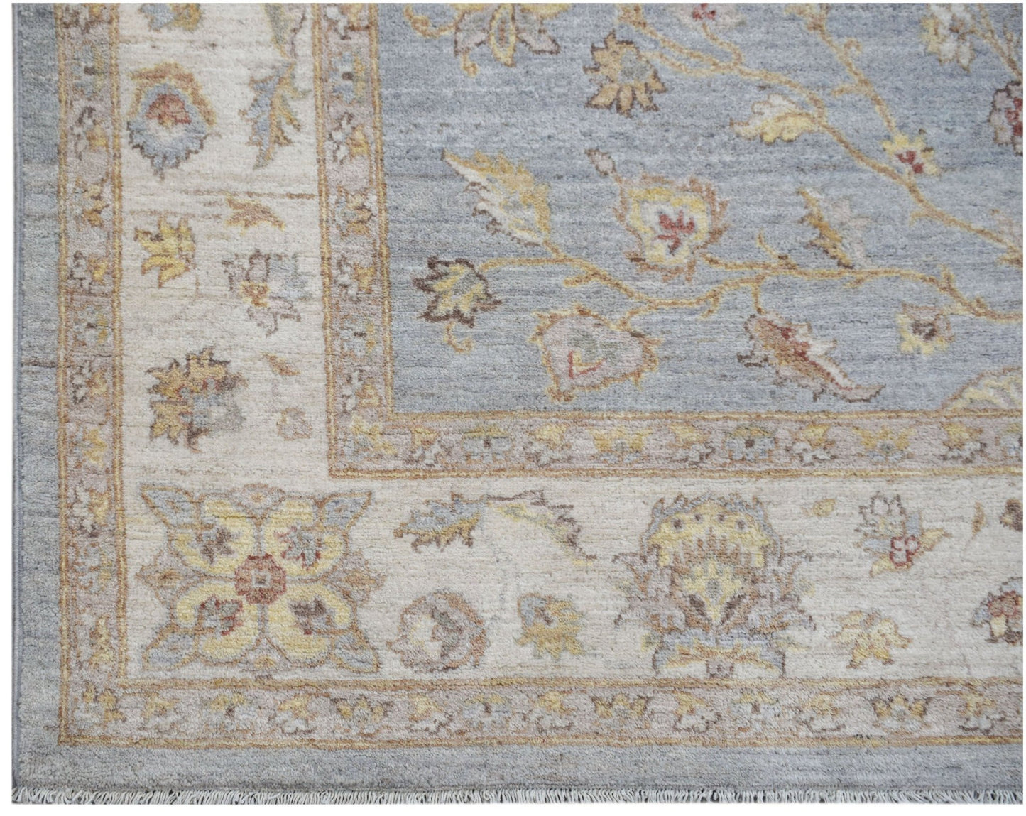 A handmade Afghan Chobi rug featuring a blue field with floral patterns and a cream border.