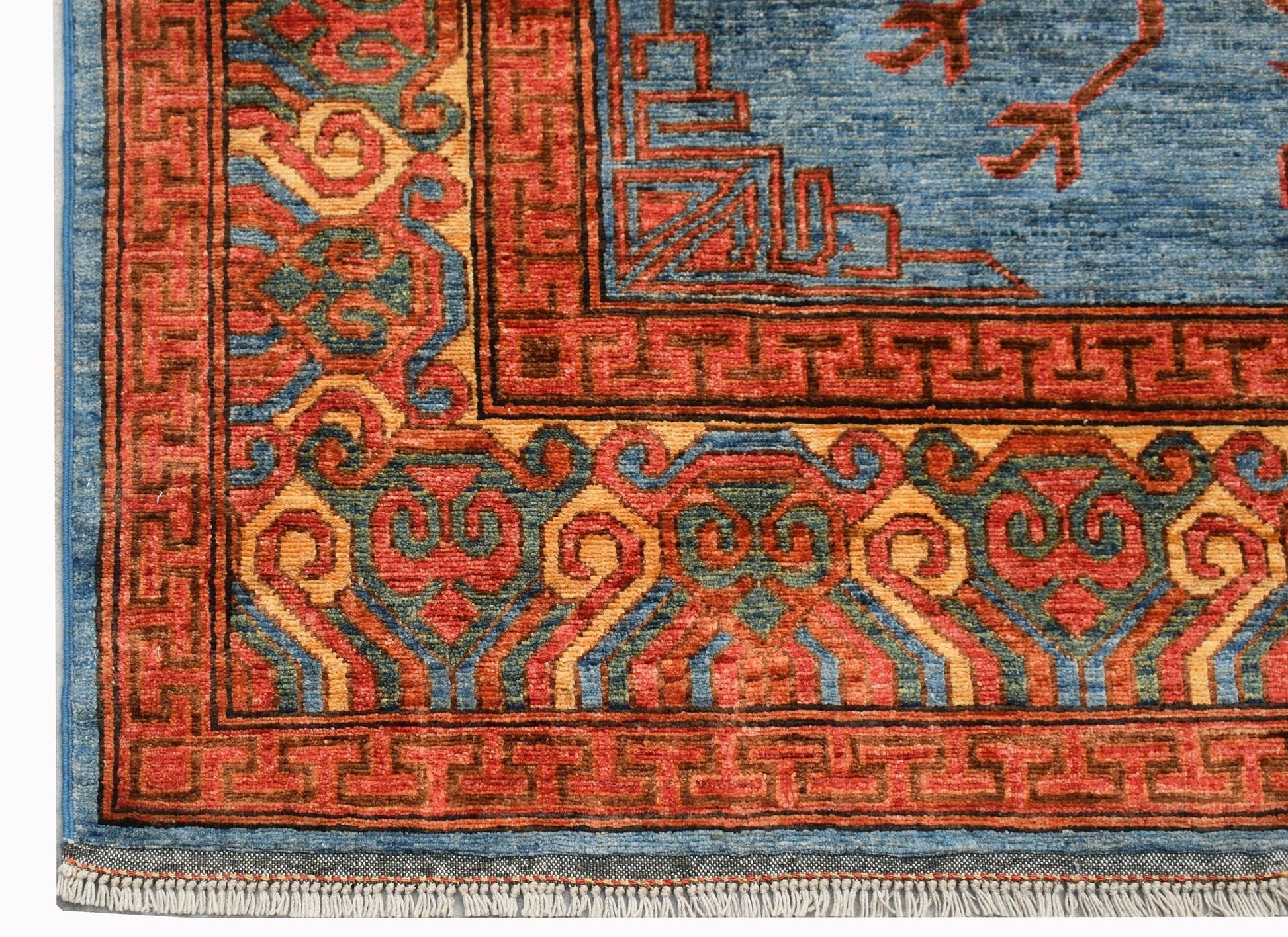 A handwoven Afghan Chobi rug featuring a blue field with geometric patterns and a red border.