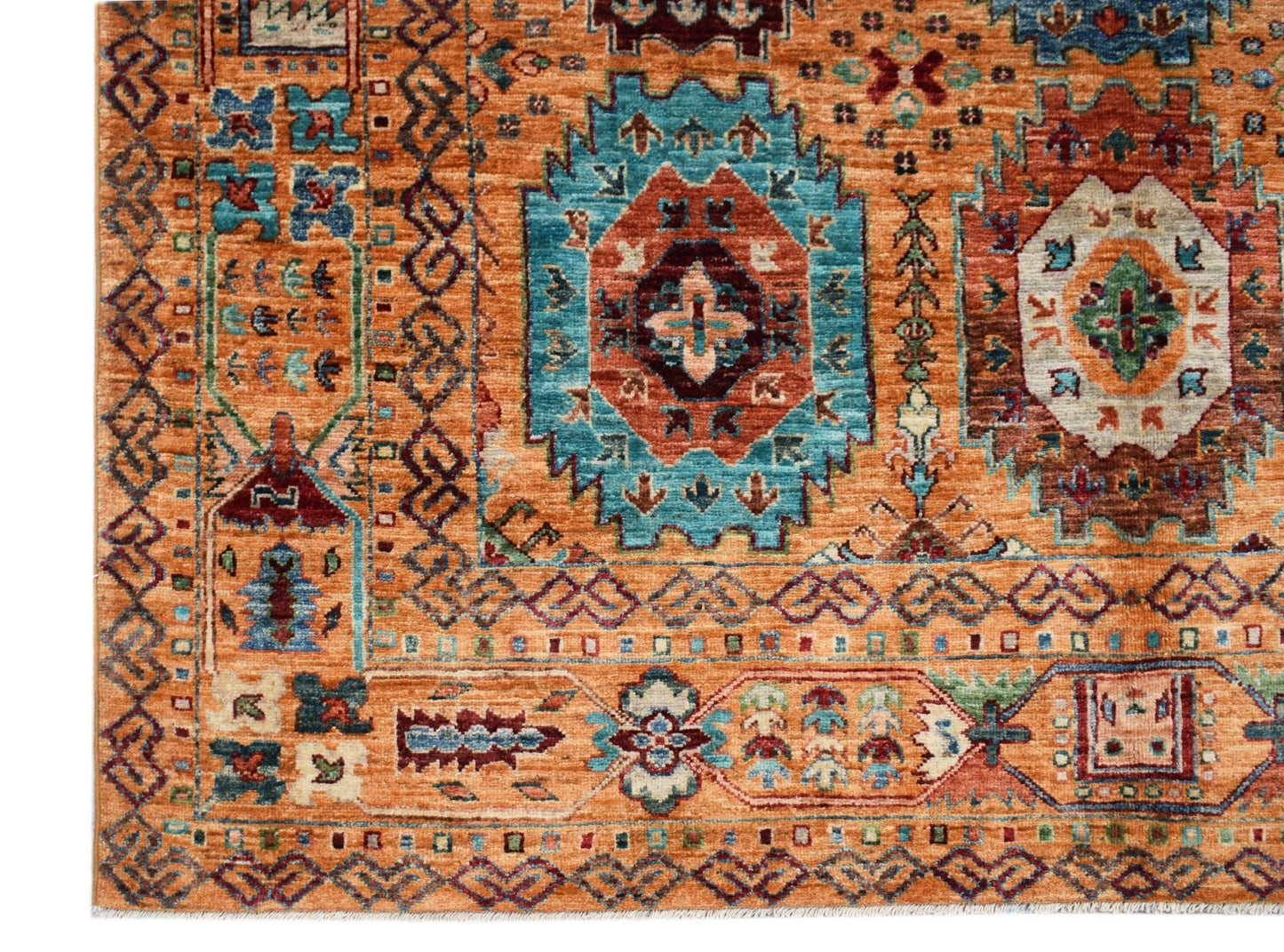 A handmade Afghan Chobi rug featuring intricate geometric patterns in warm orange and blue tones.