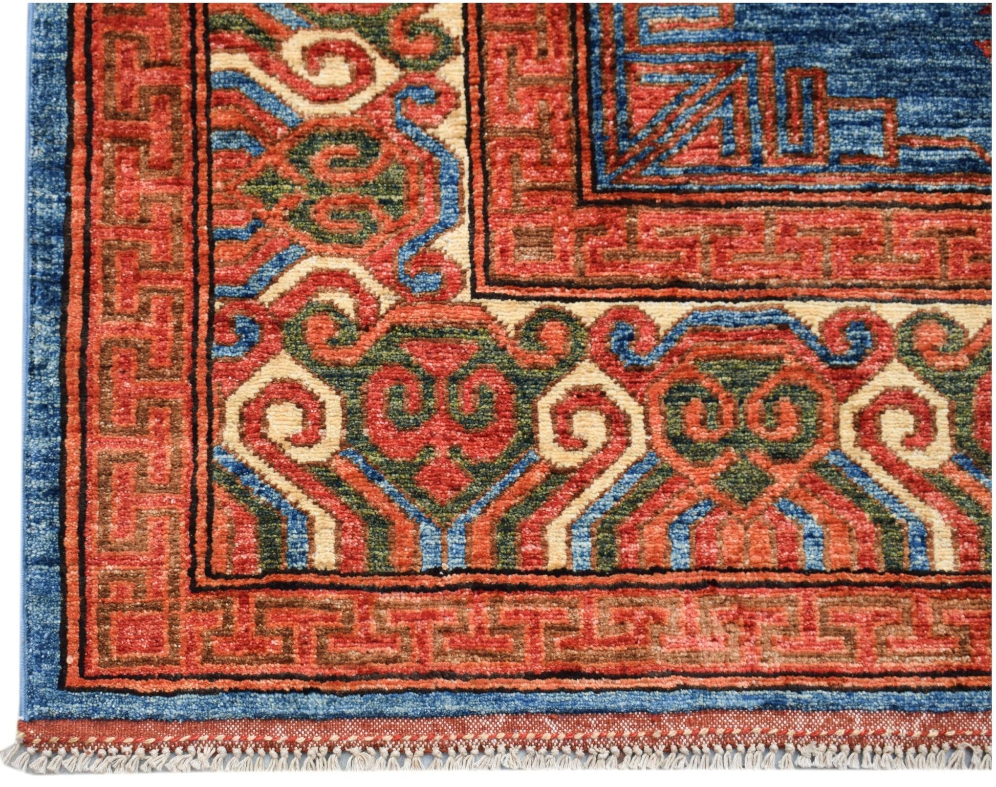 A corner view of a handwoven Afghan Chobi rug featuring intricate geometric patterns in red and blue.