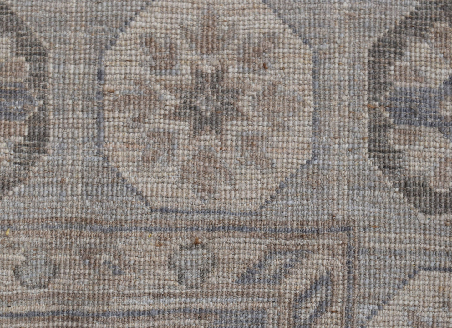 A close-up of a handwoven Afghan Chobi rug featuring a traditional geometric pattern in neutral tones.