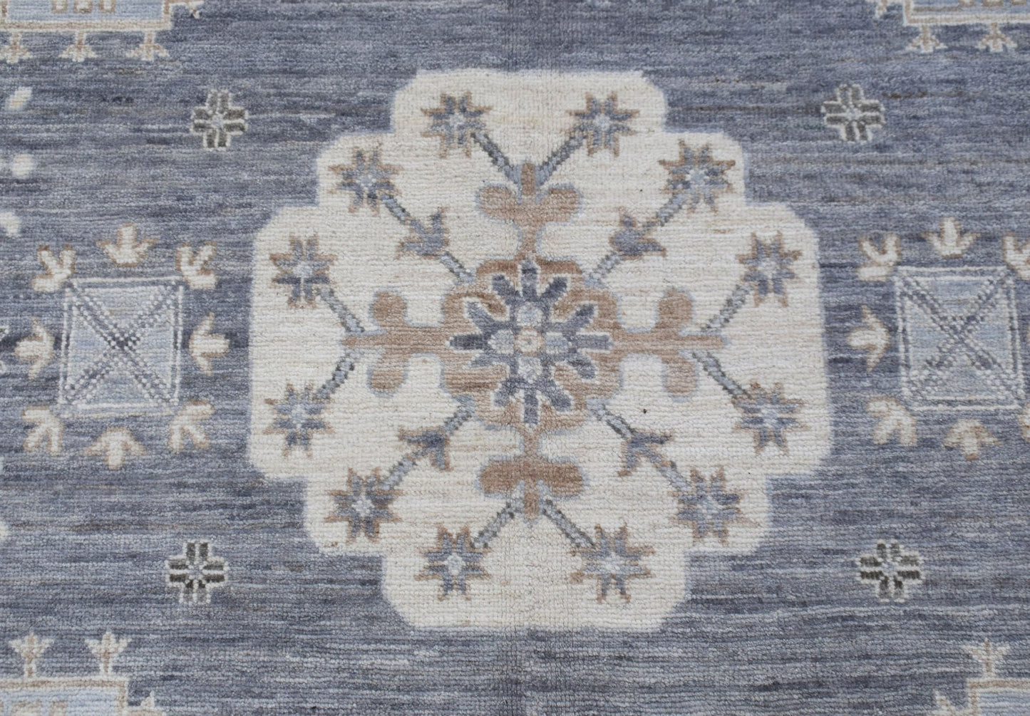 A handmade Afghan Chobi rug featuring a central floral medallion on a textured blue background.