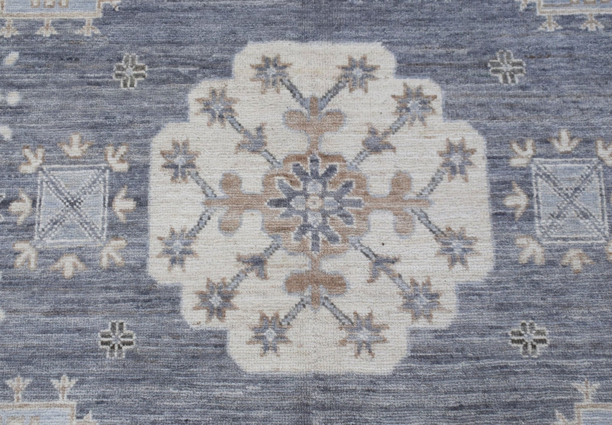 A handmade Afghan Chobi rug featuring a central floral medallion on a textured blue background.