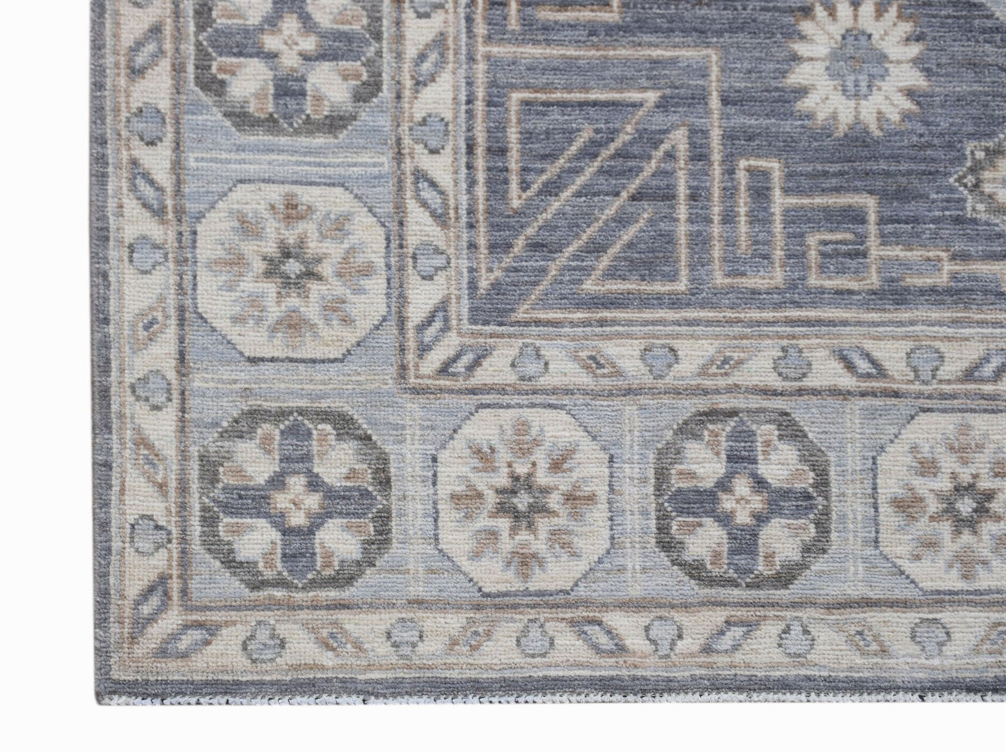 A handwoven Afghan Chobi rug featuring geometric floral motifs in shades of blue, grey, and beige.