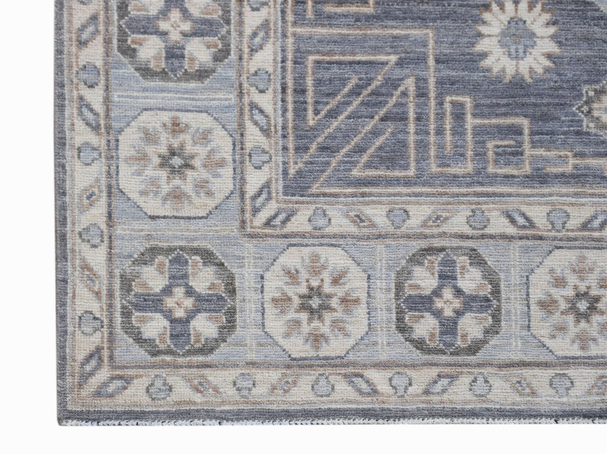 A handwoven Afghan Chobi rug featuring geometric floral motifs in shades of blue, grey, and beige.