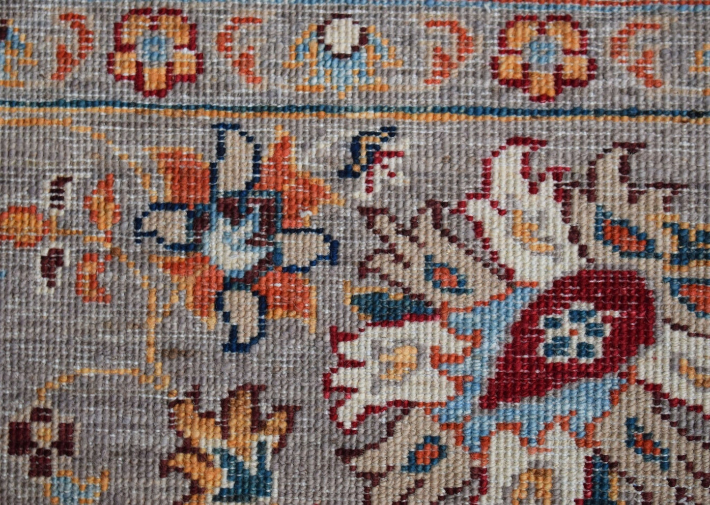 A close-up of a handwoven Afghan Chobi rug featuring intricate floral patterns in warm earth tones.