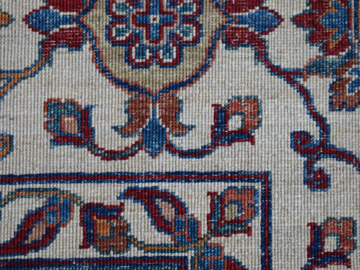 A close-up of an Afghan Chobi rug featuring intricate floral patterns in red, blue, and tan wool.