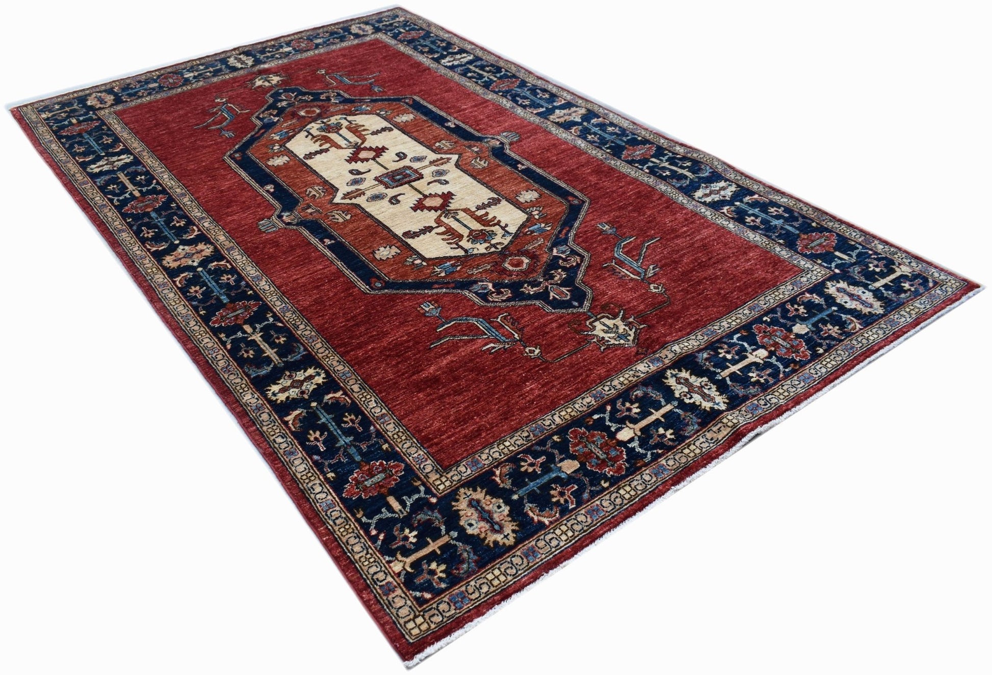 An Afghan Chobi rug featuring a central medallion on a red field with a dark blue floral border.