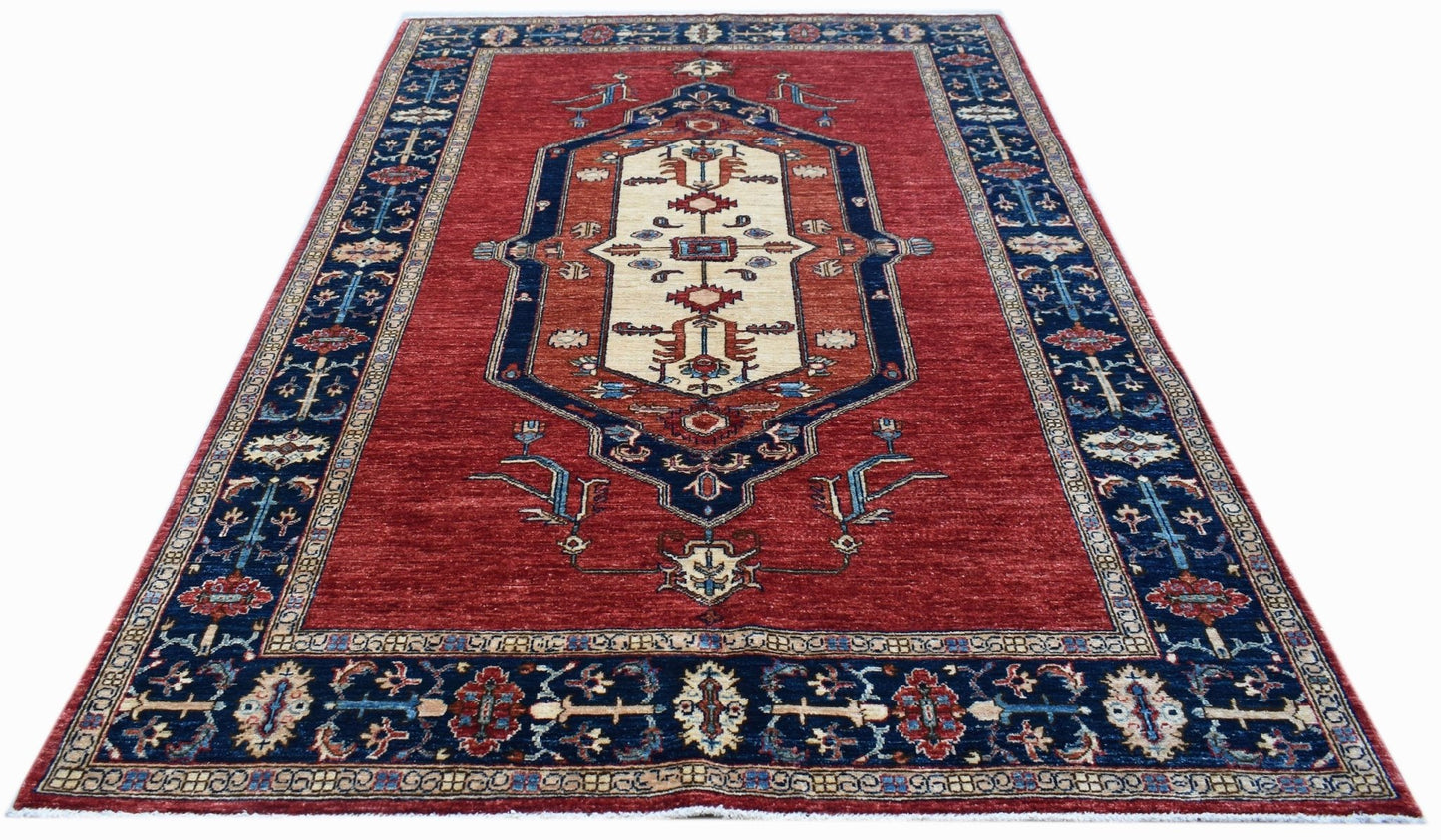 Handwoven Afghan Chobi rug featuring a traditional geometric medallion on a red field.