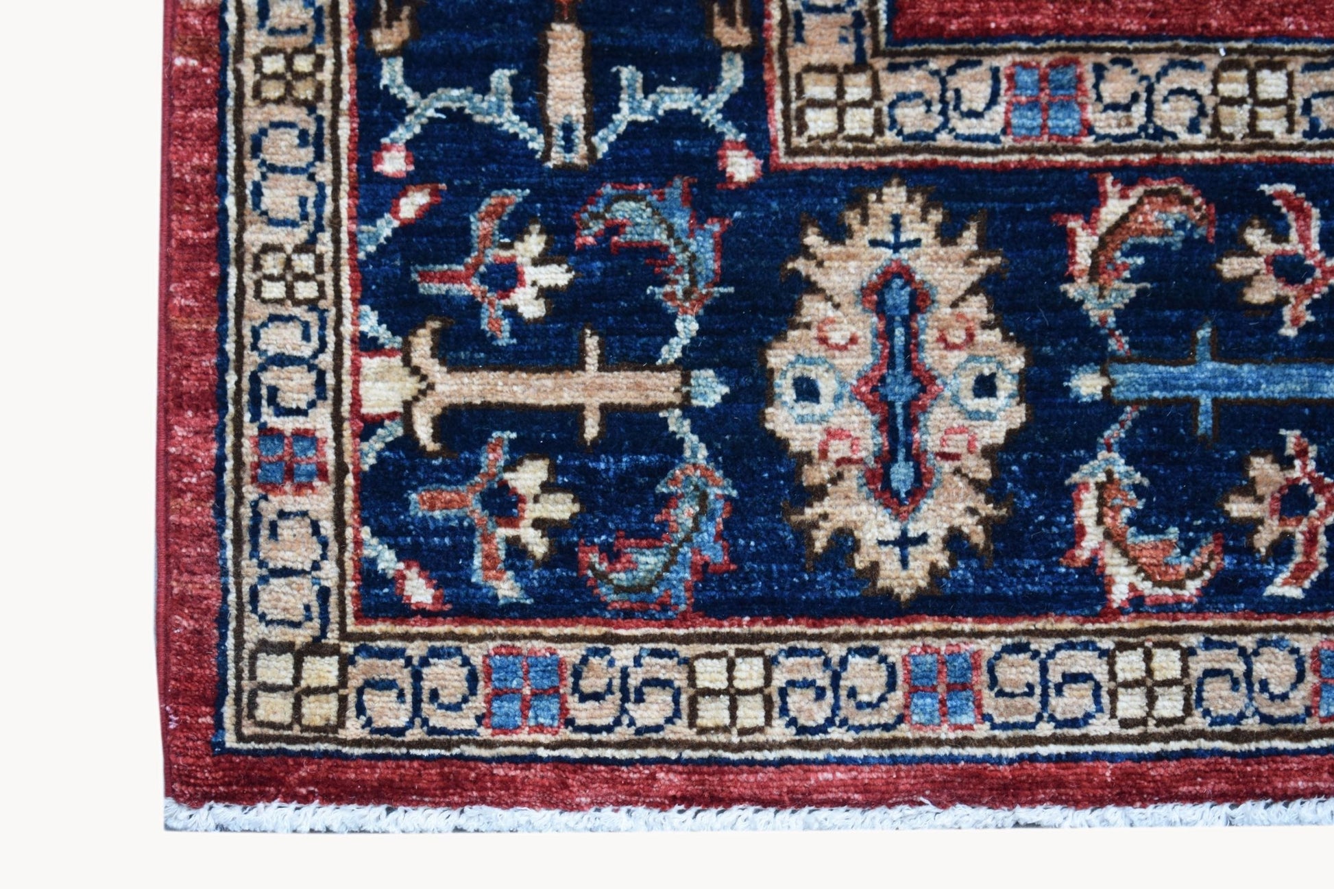 A close-up of a handmade Afghan Chobi rug featuring a blue field with intricate floral patterns.