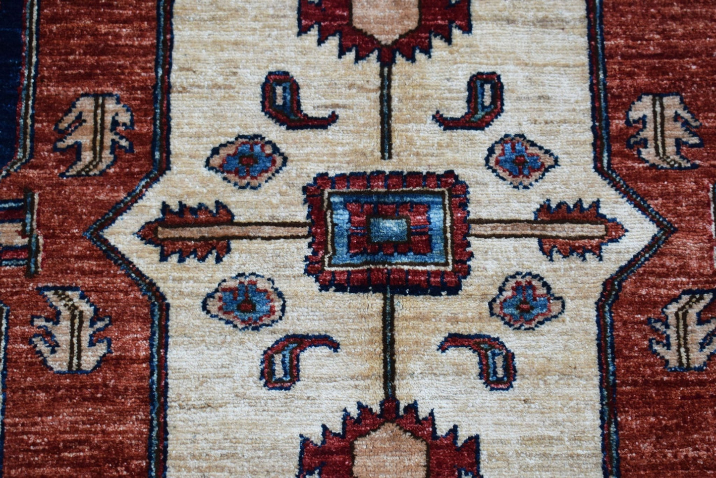 A handwoven Afghan Chobi rug featuring a central geometric medallion on a cream field.