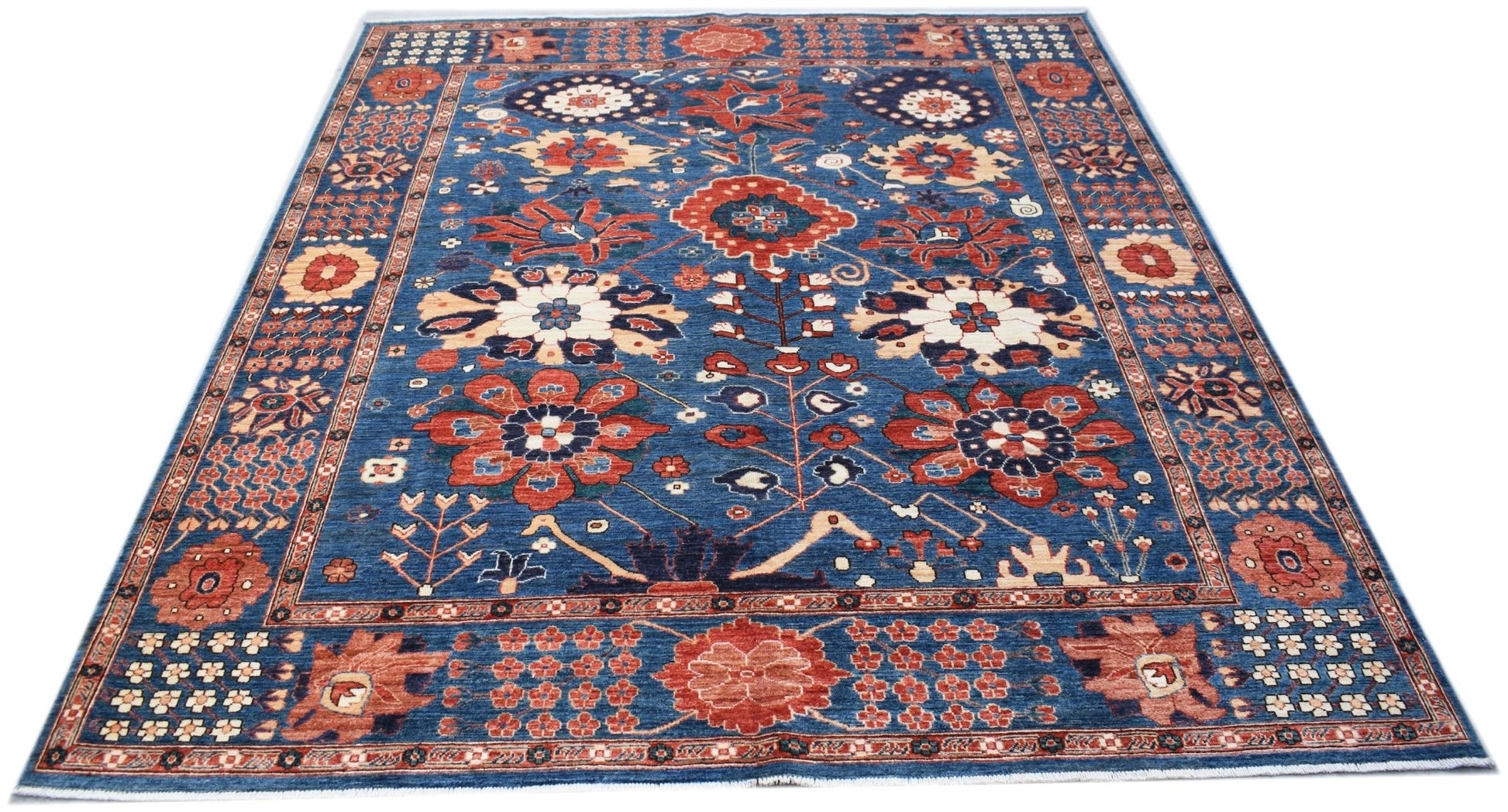 A rectangular Afghan Chobi rug featuring a blue field with intricate floral and botanical patterns.