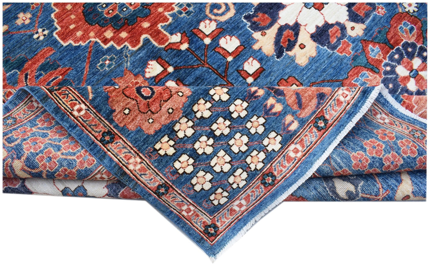 A handwoven Afghan Chobi rug featuring a blue field with floral patterns and a folded corner.