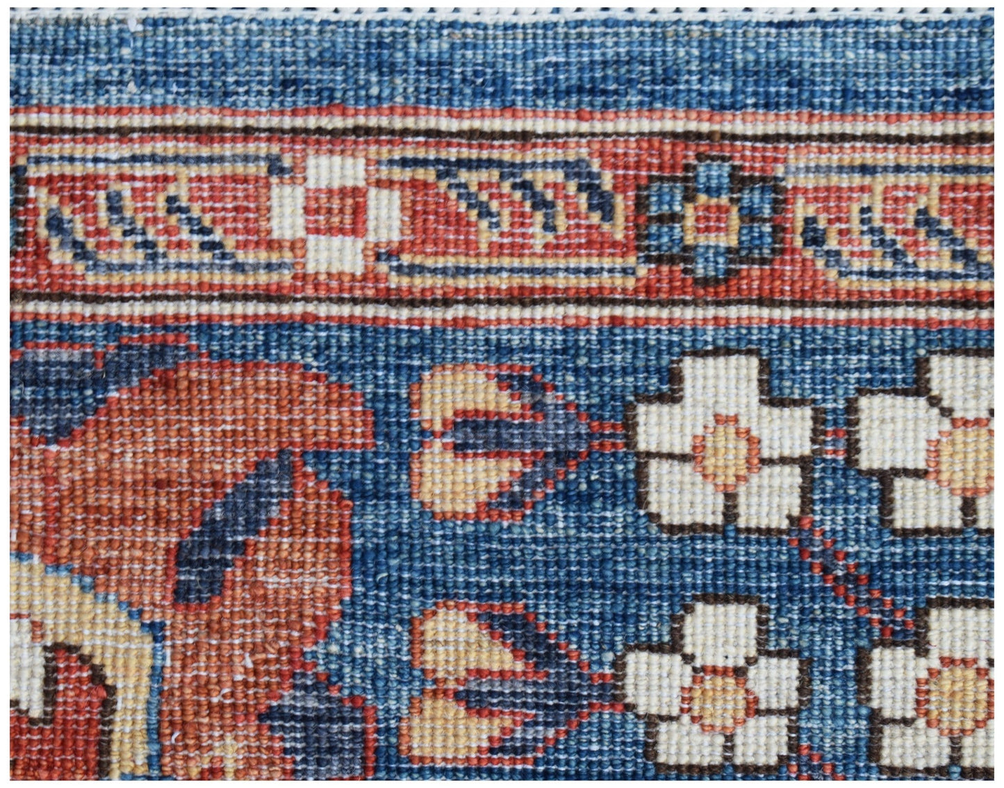 A close-up of a handmade Afghan Chobi rug featuring intricate floral patterns in blue and red.