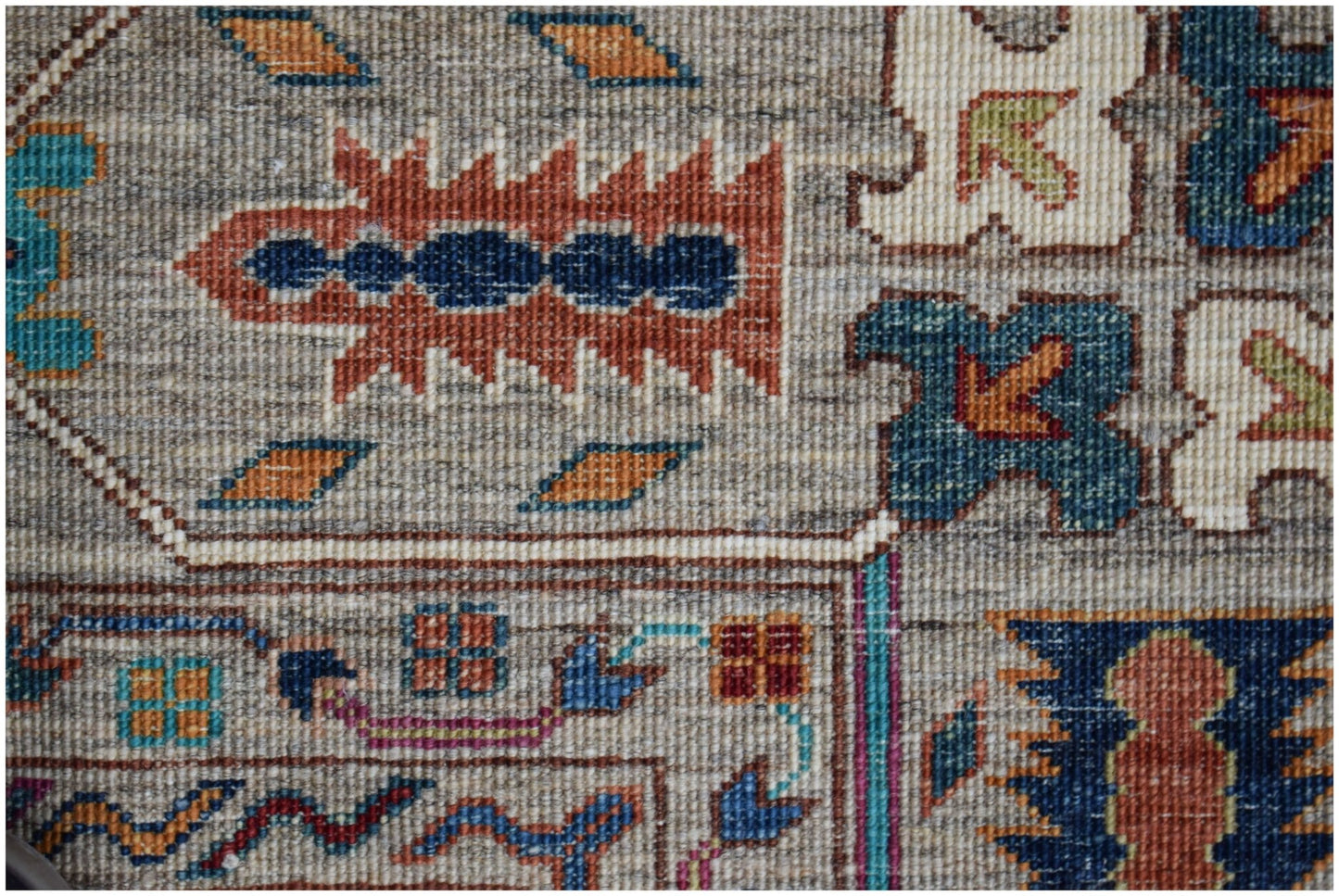 A close-up of an Afghan Chobi rug featuring intricate geometric patterns in earthy tones.