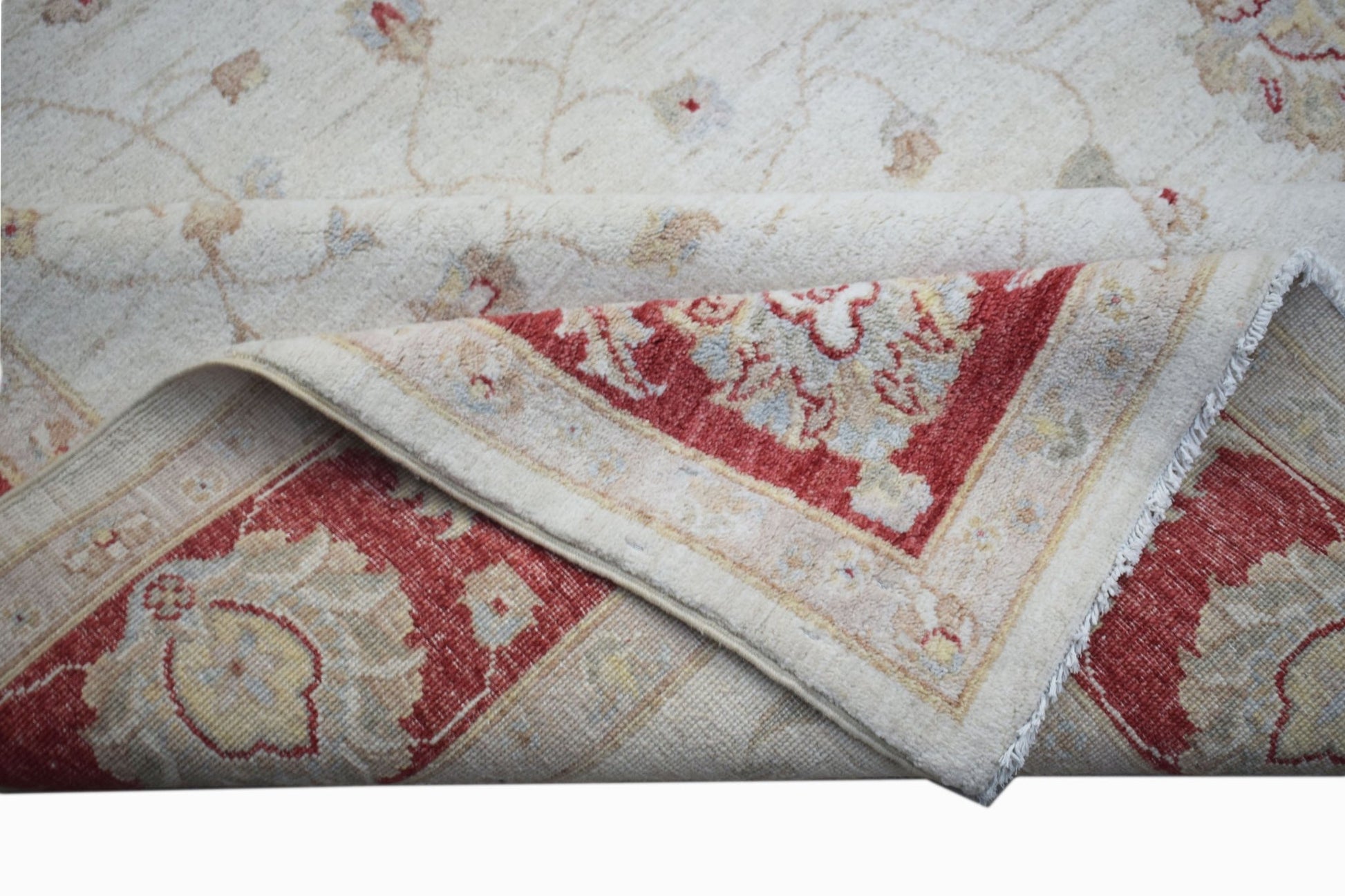 A handwoven Afghan Chobi rug with a cream field and a red floral border, shown folded.