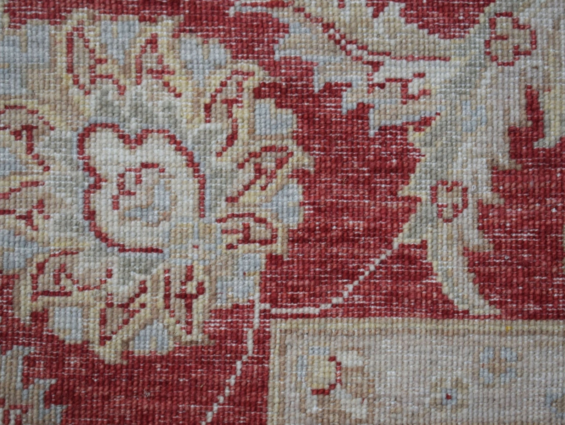 A close-up of a handwoven Afghan Chobi rug featuring intricate floral patterns in red and beige.