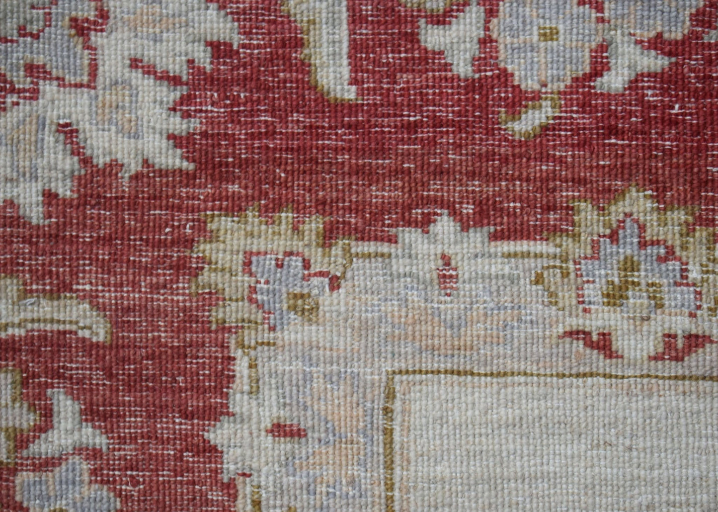 A close-up of a handwoven Afghan Chobi rug featuring intricate floral patterns in red and beige.