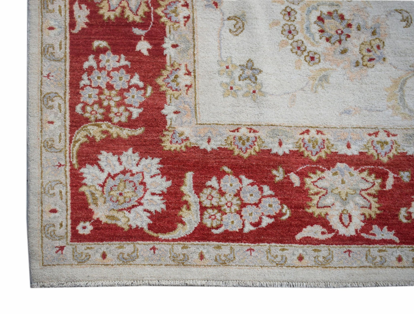 A handwoven Afghan Chobi rug featuring a red border with floral patterns and a cream center.