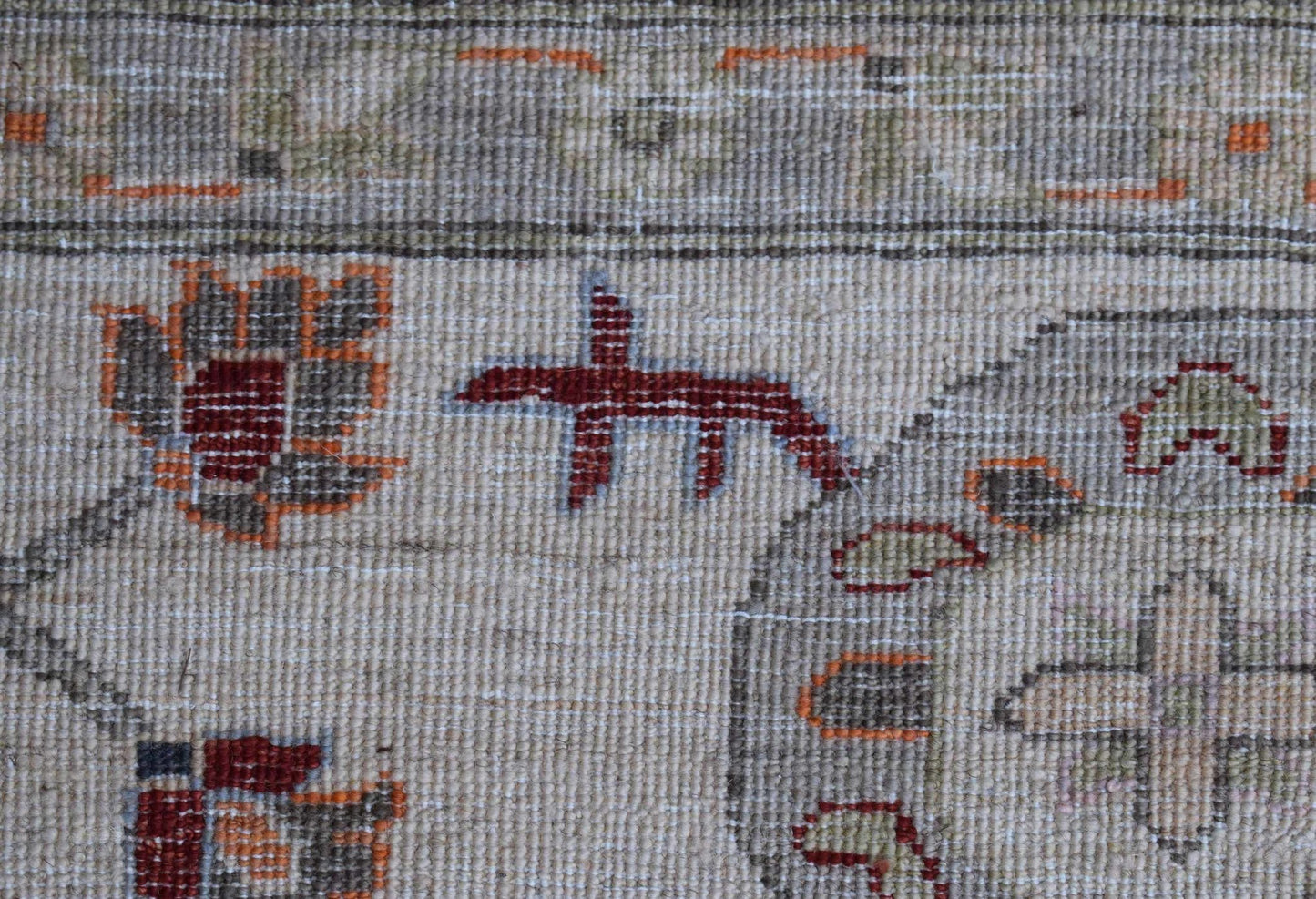 A close-up of a handwoven Afghan Chobi rug featuring traditional floral motifs in earthy tones.