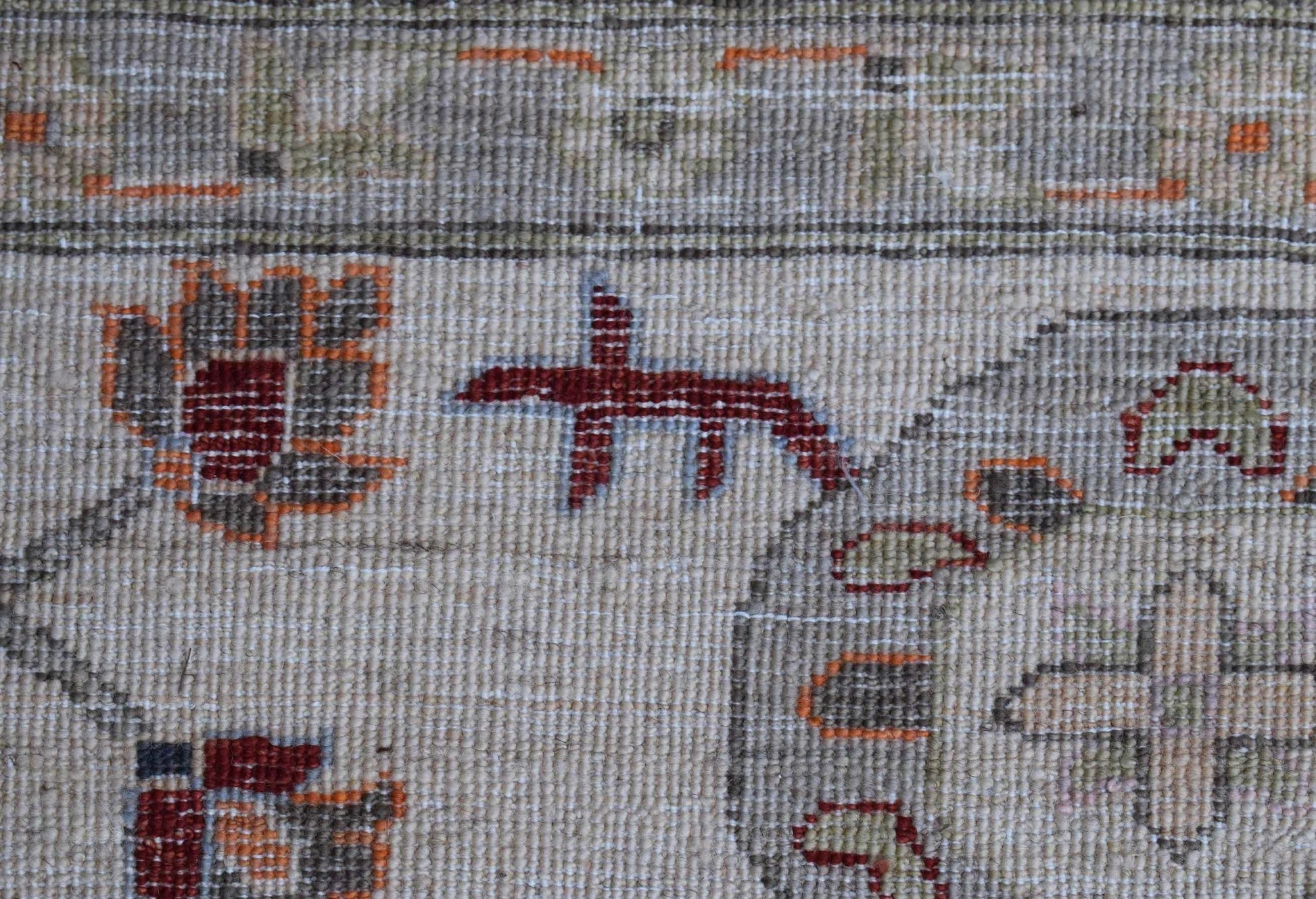 A close-up of a handwoven Afghan Chobi rug featuring traditional floral motifs in earthy tones.