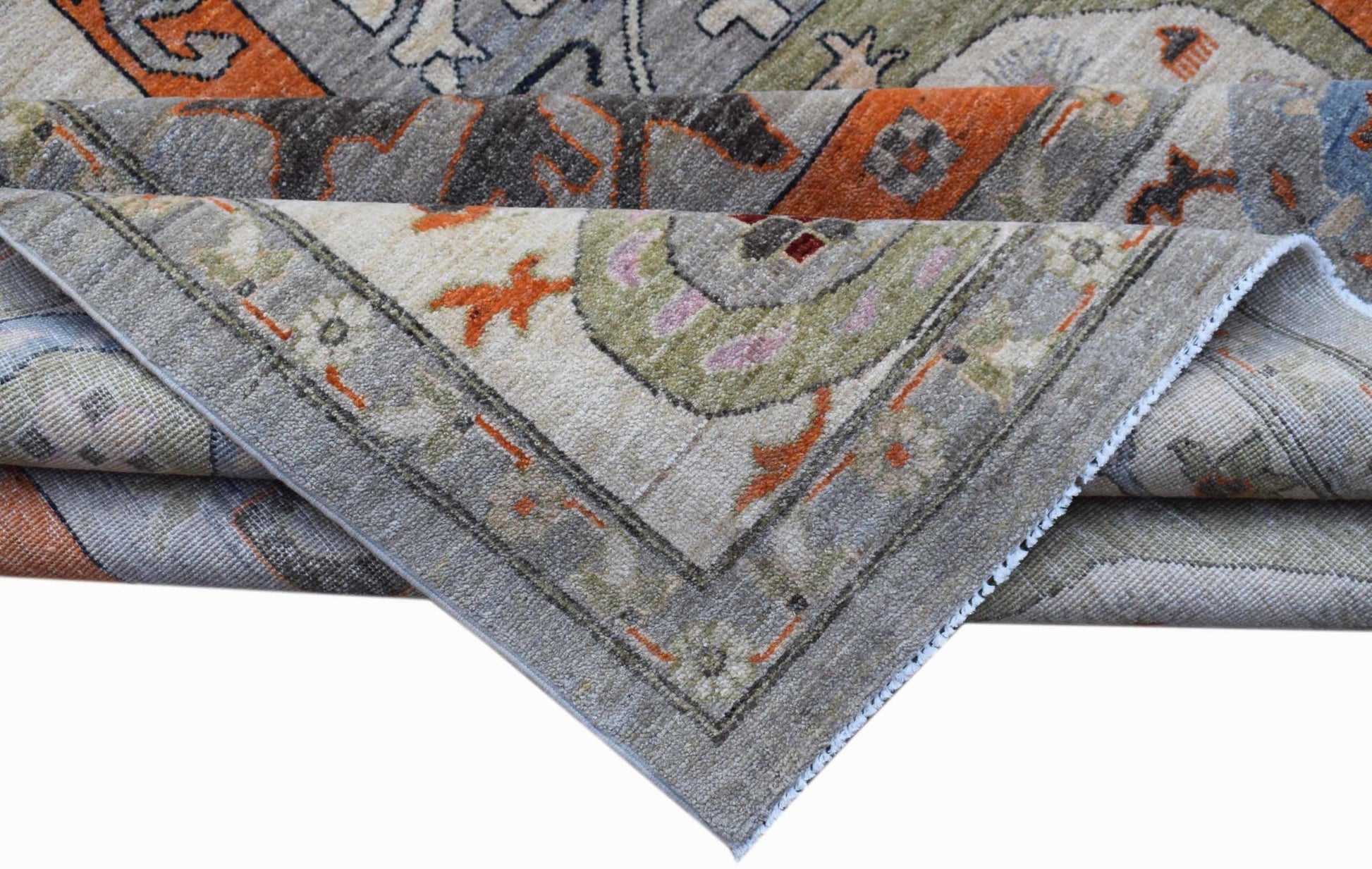 A folded Afghan Chobi rug featuring traditional patterns in shades of grey, orange, and green.