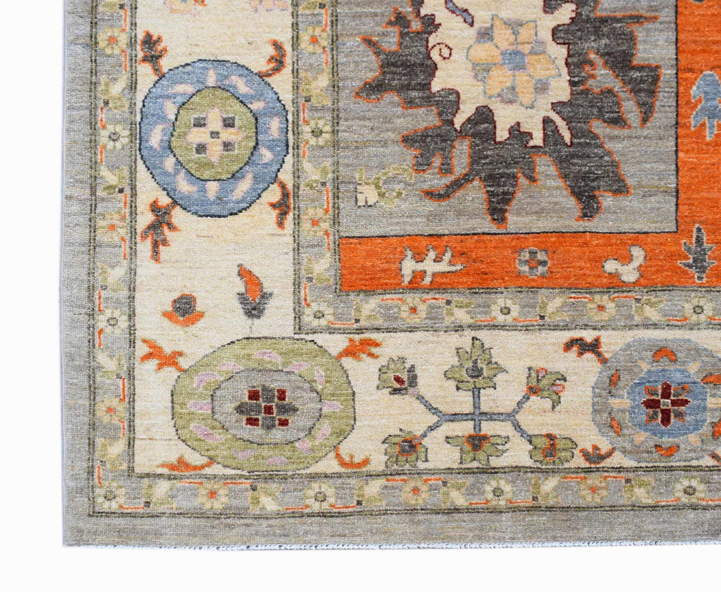 A handmade Afghan Chobi rug featuring traditional floral motifs in orange, blue, and cream tones.