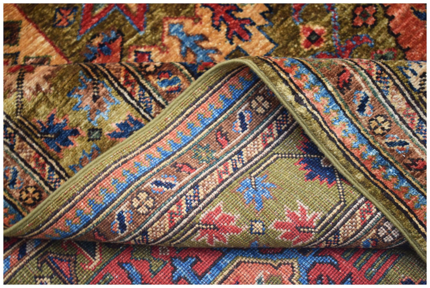 A corner of a handwoven Afghan Chobi rug featuring traditional floral patterns in earthy tones.