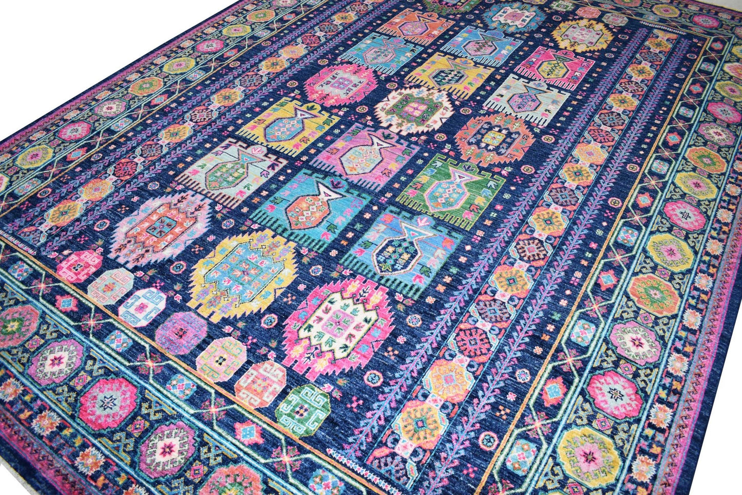 A handmade Afghan Chobi rug featuring a vibrant, multi-colored geometric pattern on a blue field.
