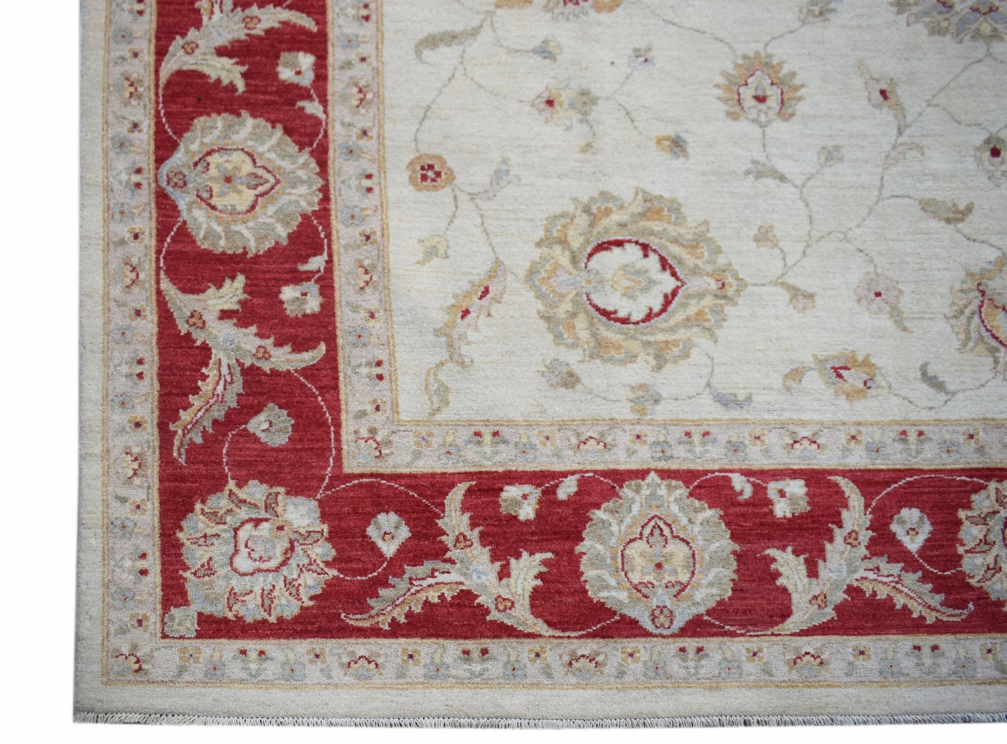 A handmade Afghan Chobi rug featuring a cream field with floral motifs and a red border.